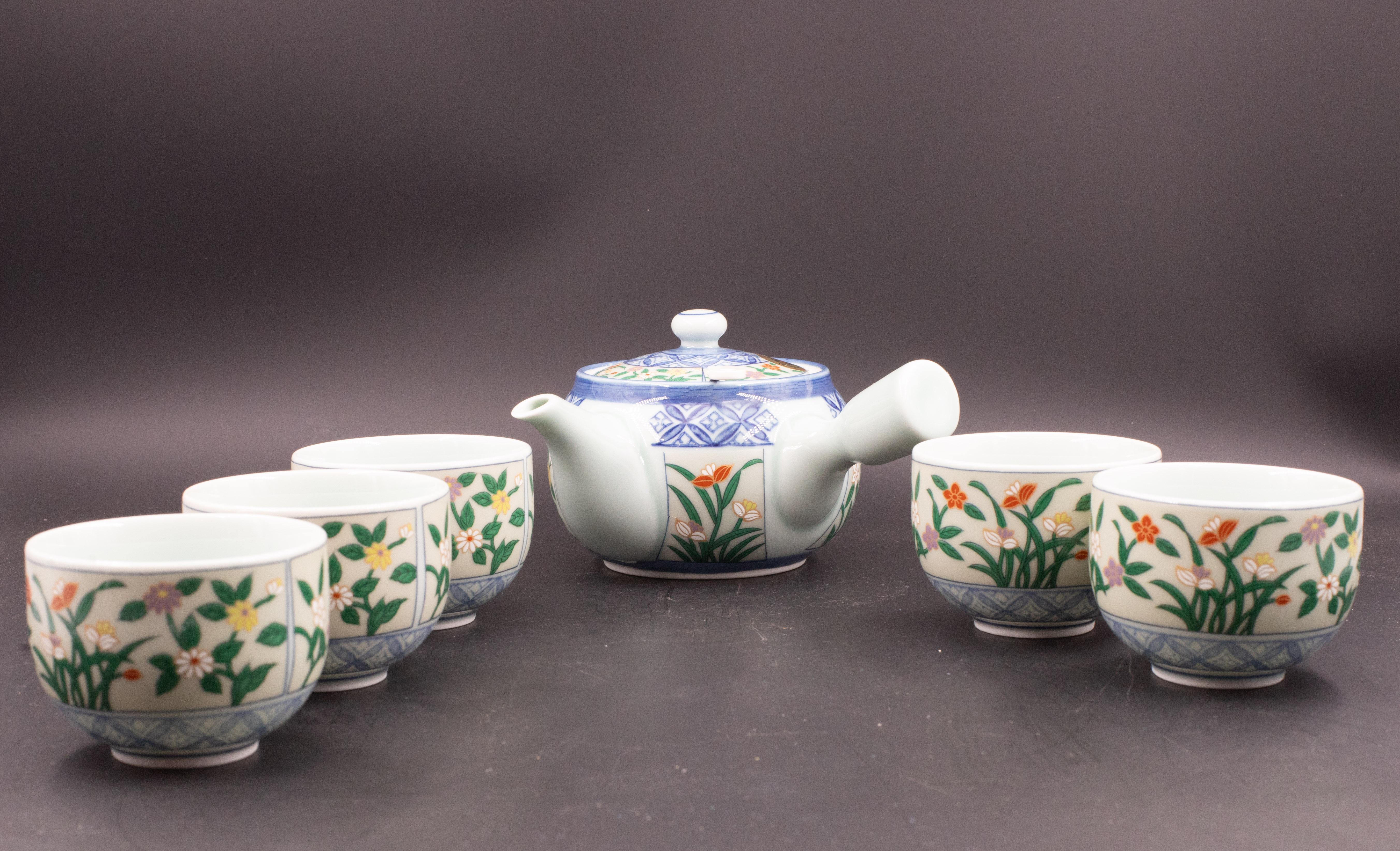 Pretty Japanese tea set with teapot, lid, metal strainer with bamboo handle and 5 cups.
Soft celadon is accented by bright blue and hand-painted irises and mummies. 
Cheerful colors: green, purple, yellow, white and orange.
Traditional kyusu-style
