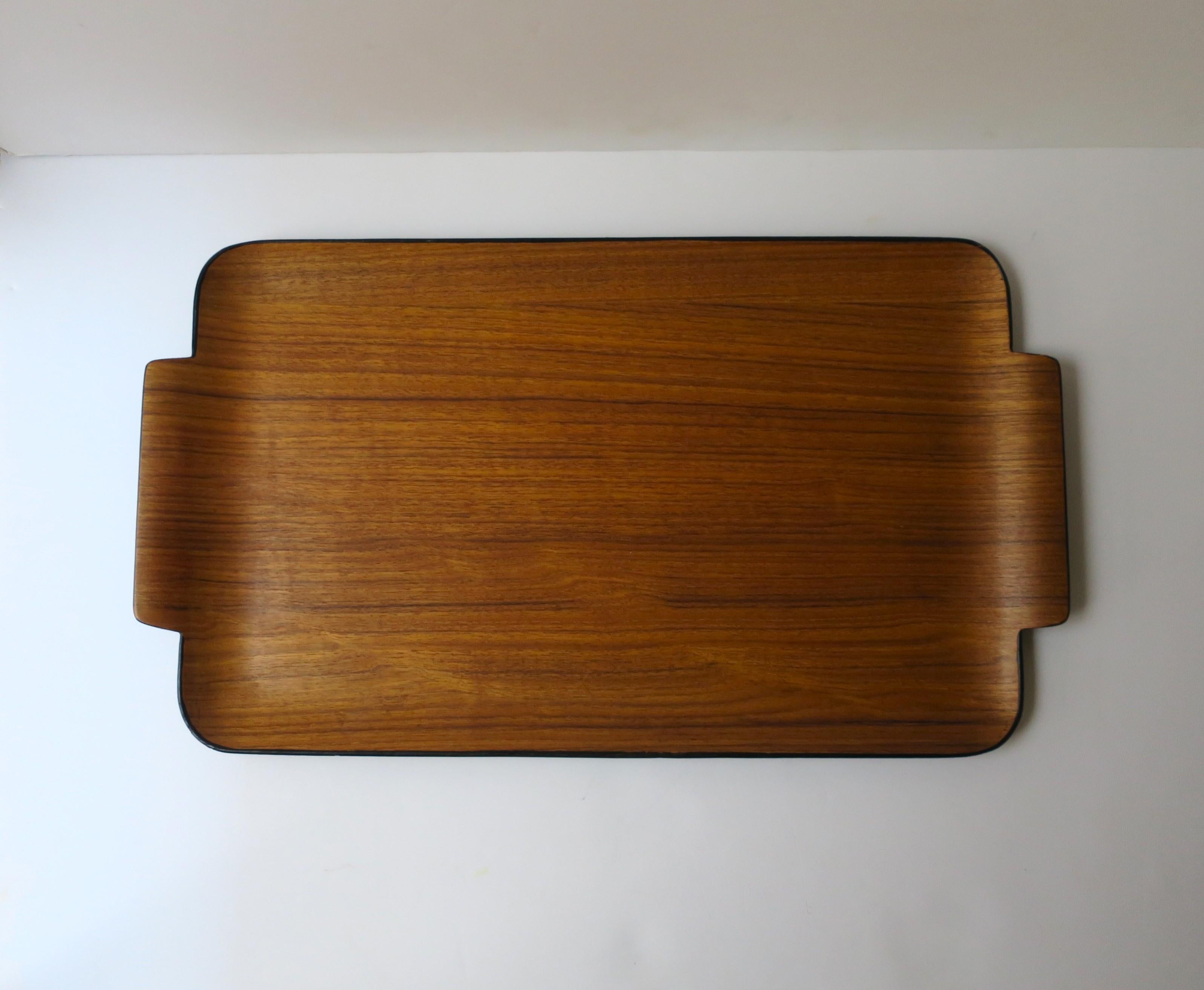 A beautiful Japanese teak serving tray, Midcentury Modern design period, circa mid-20th century, 1960s, Japan. Tray is a warm brown teak, strategically arched design around, sleek 'handles', finish with a matte black edge and underside. Beautiful