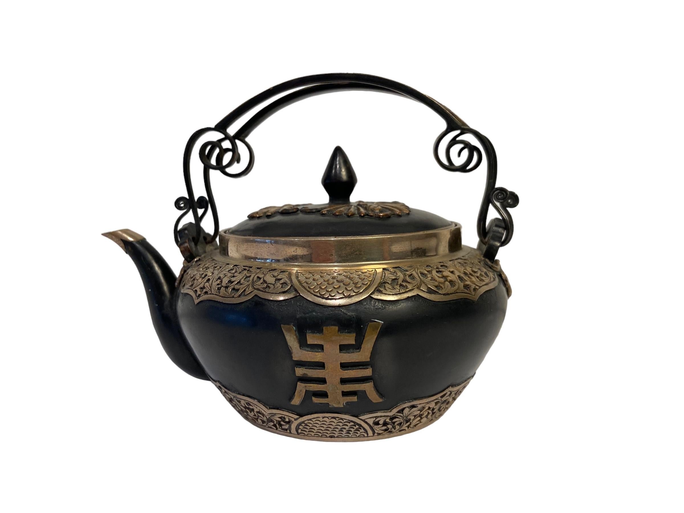 Tetera japonesa de bronce con adornos de plata.
Periodo Meiji (1868 -1912), hacia 1880. 
H: 12 cm.  Anchura: 15,5 cm.  D: 12 cm.