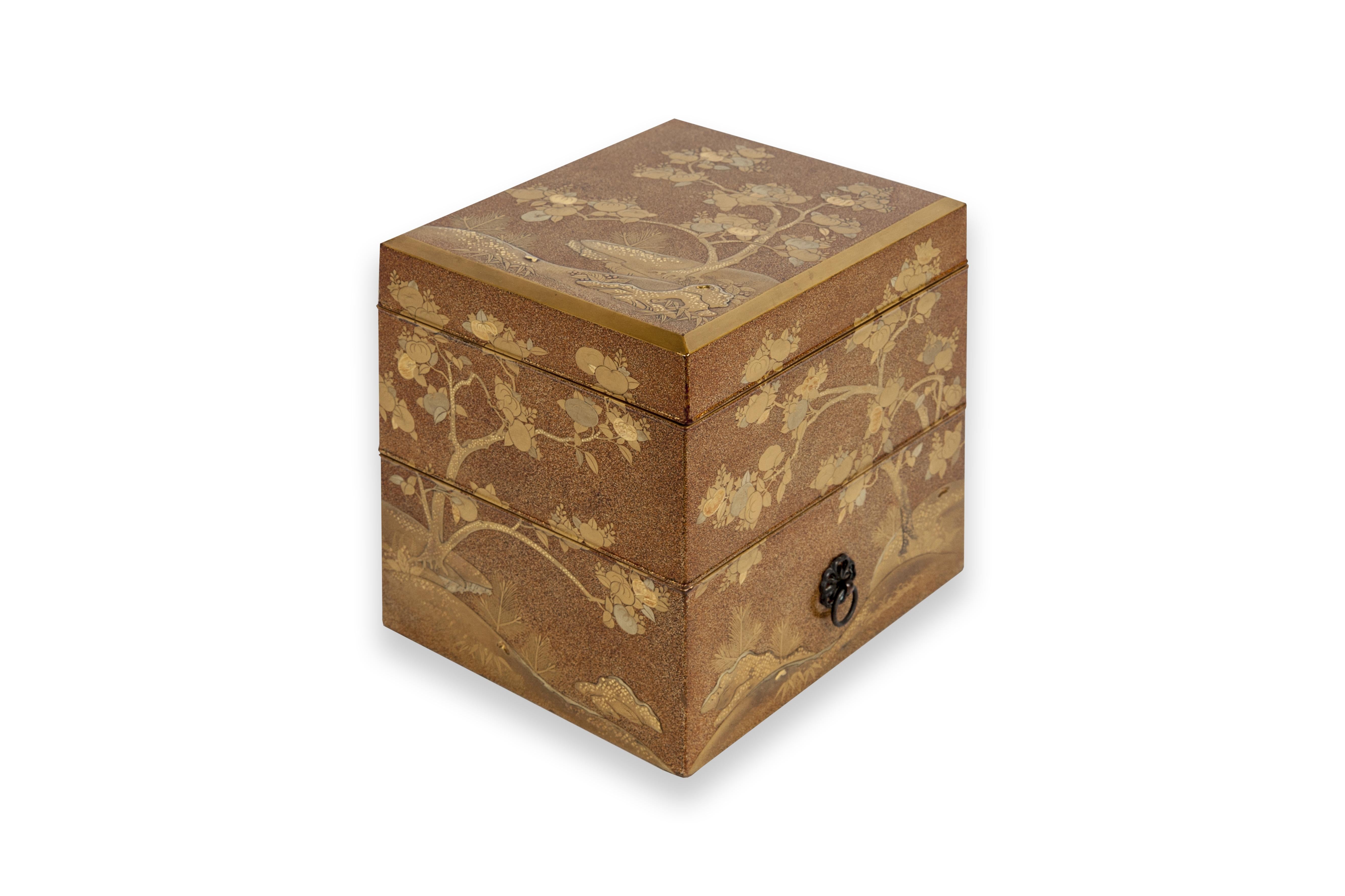 Tebako box with two compartments in golden and nashi-ji lacquer, decorated with golden, red, and kirigane lacquer, golden persimmon tree leaves, among rocks. The compartments are of increasing size from the top. The decoration is in continuity.