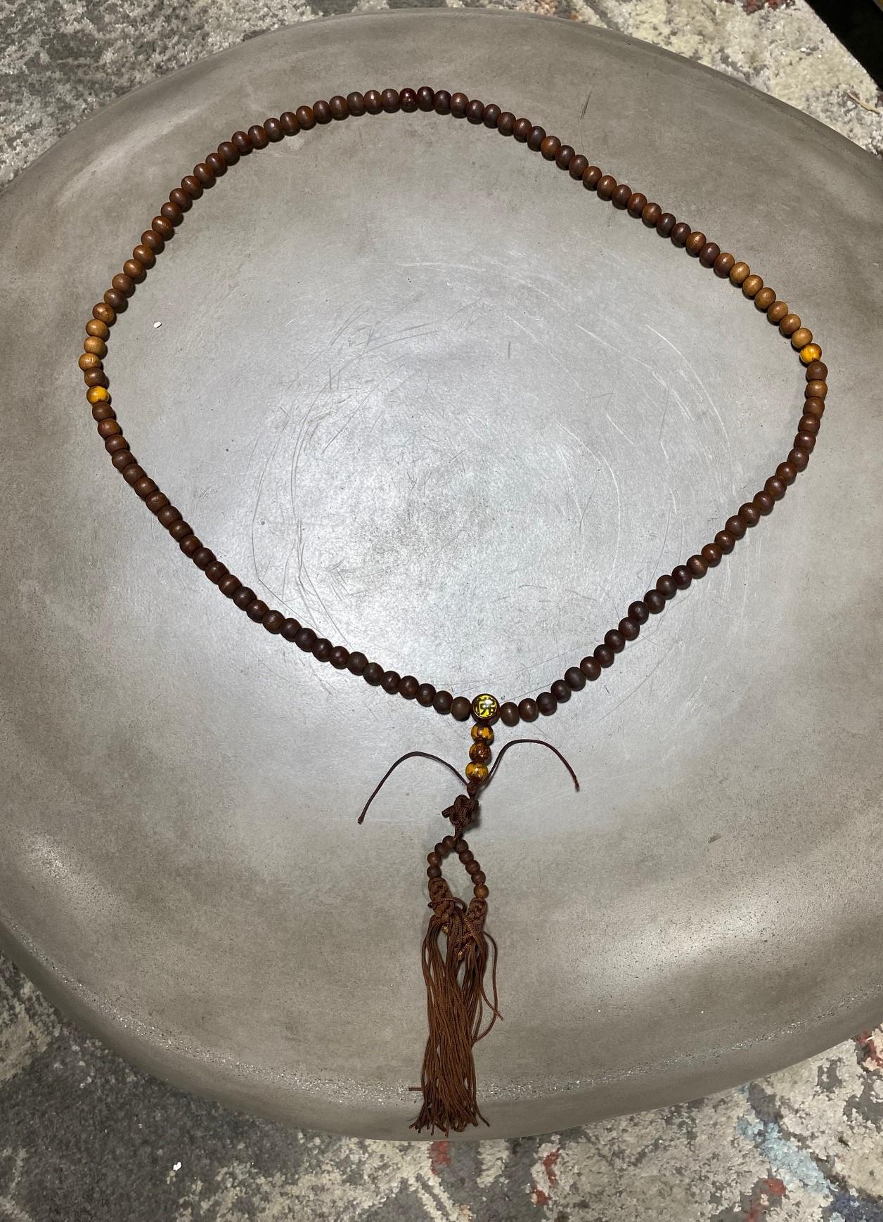 A beautiful string of Japanese hand-crafted natural wooden Buddhist Juzu mala beads made of wood, except for the large one which has glass insets. The kanji on one side of the glass is, 