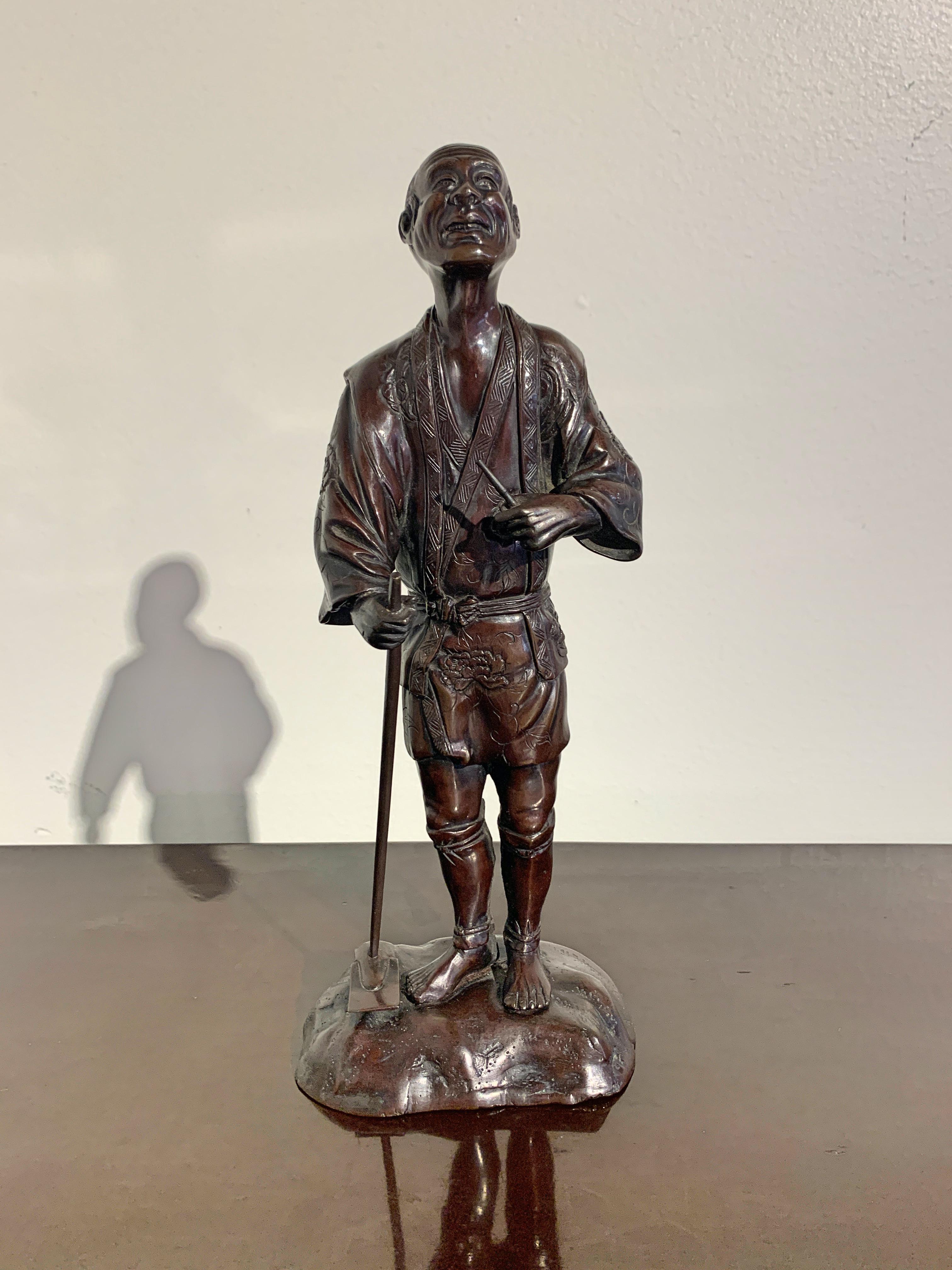 A very fine and detailed Tokyo School cast bronze okimono (decorative sculpture) of a smiling farmer, Meiji period, late 19th century, Japan. 

The elderly farmer is portrayed standing upon a patch of earth, a hoe in one hand, an awl in the other.