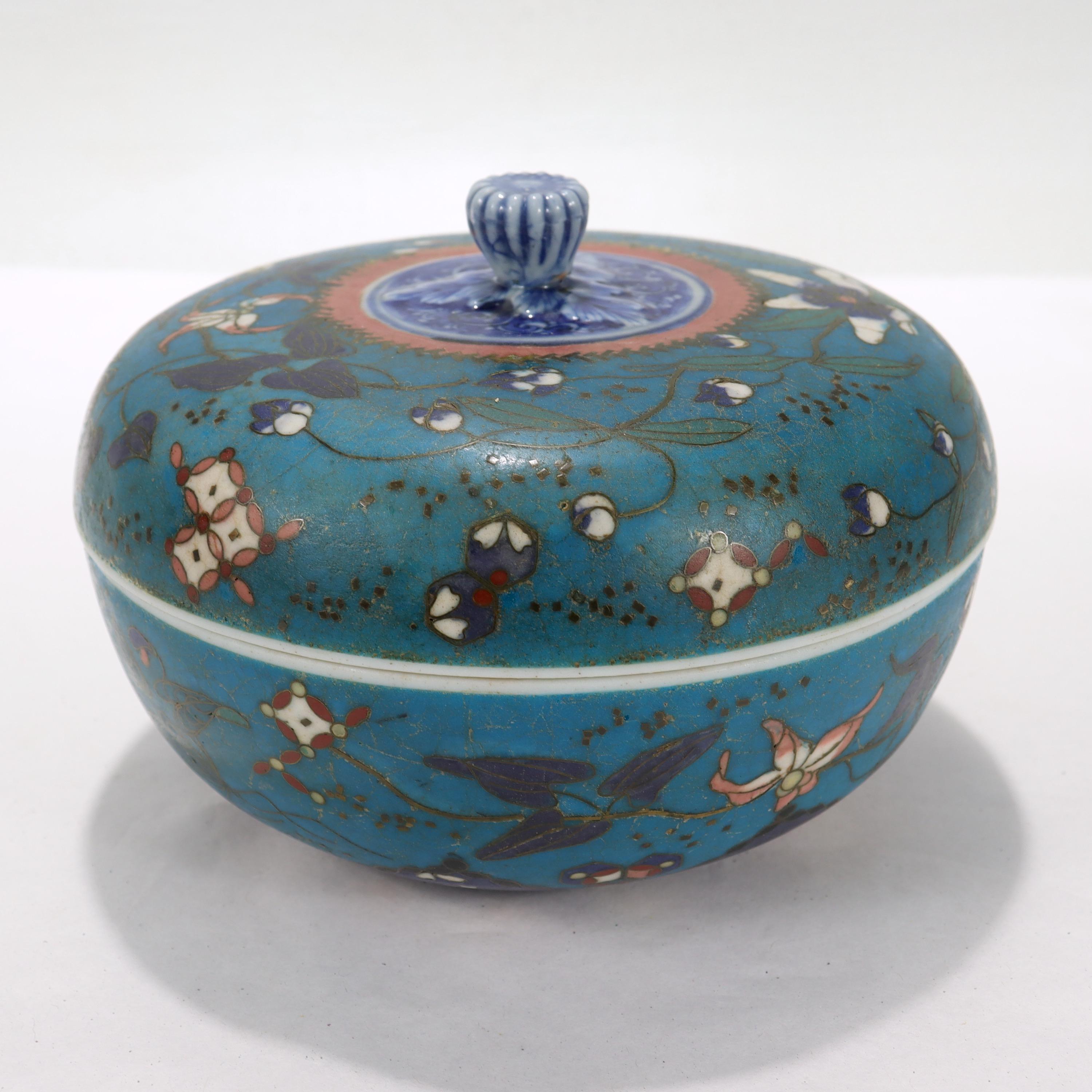 A fine Japanese porcelain box.

Decorated to the exterior with a dark turquoise enamel ground with floral decorations. The figural finial as well as the interiors of the box & lid are classic blue and white porcelain with floral decoration.

Simply