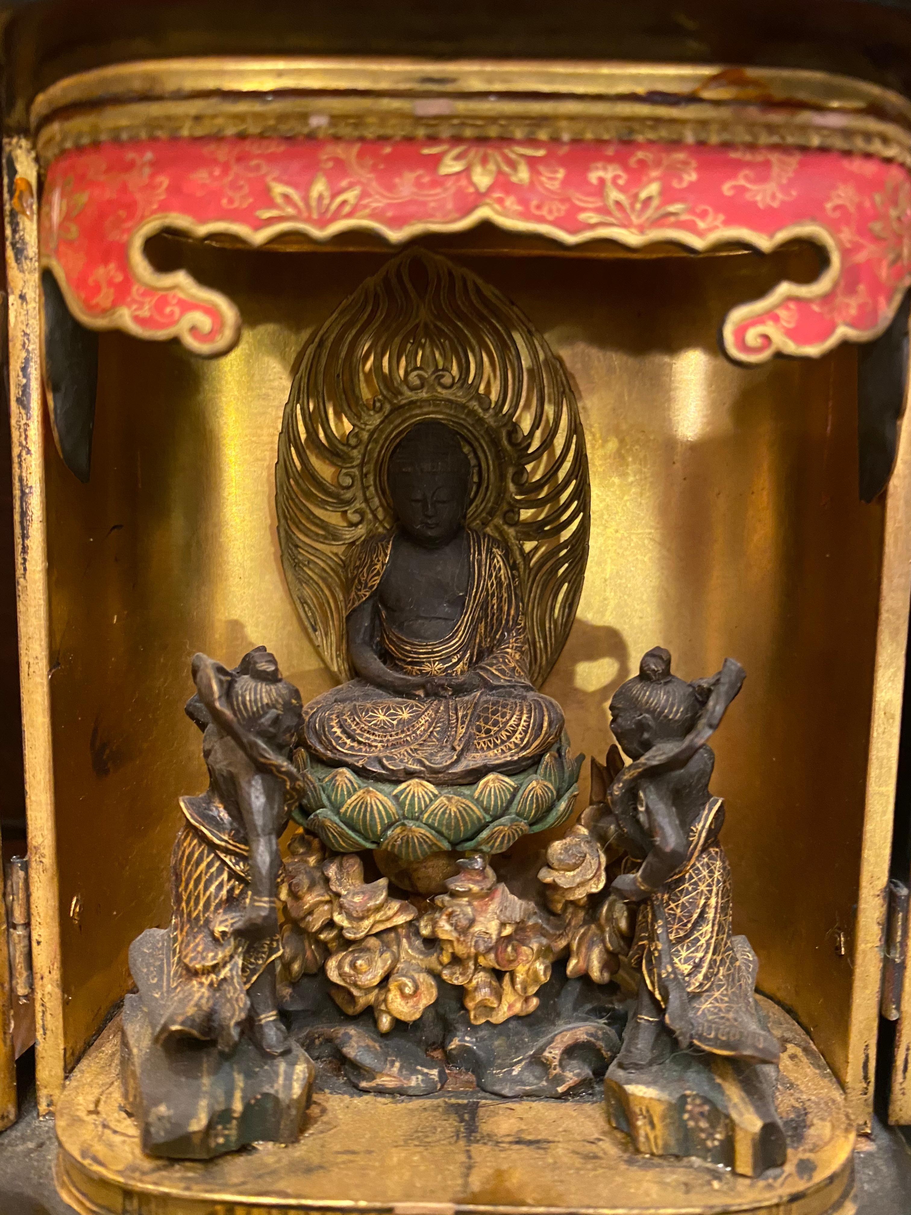 This travel shrine Buddhism temple having gold leaf, hand carved and hand painted very delicately
red lacquered trim to the front top having Buddha sitting on a lotus blossom with two attendances
red, green and black lacquers handmade lock to the