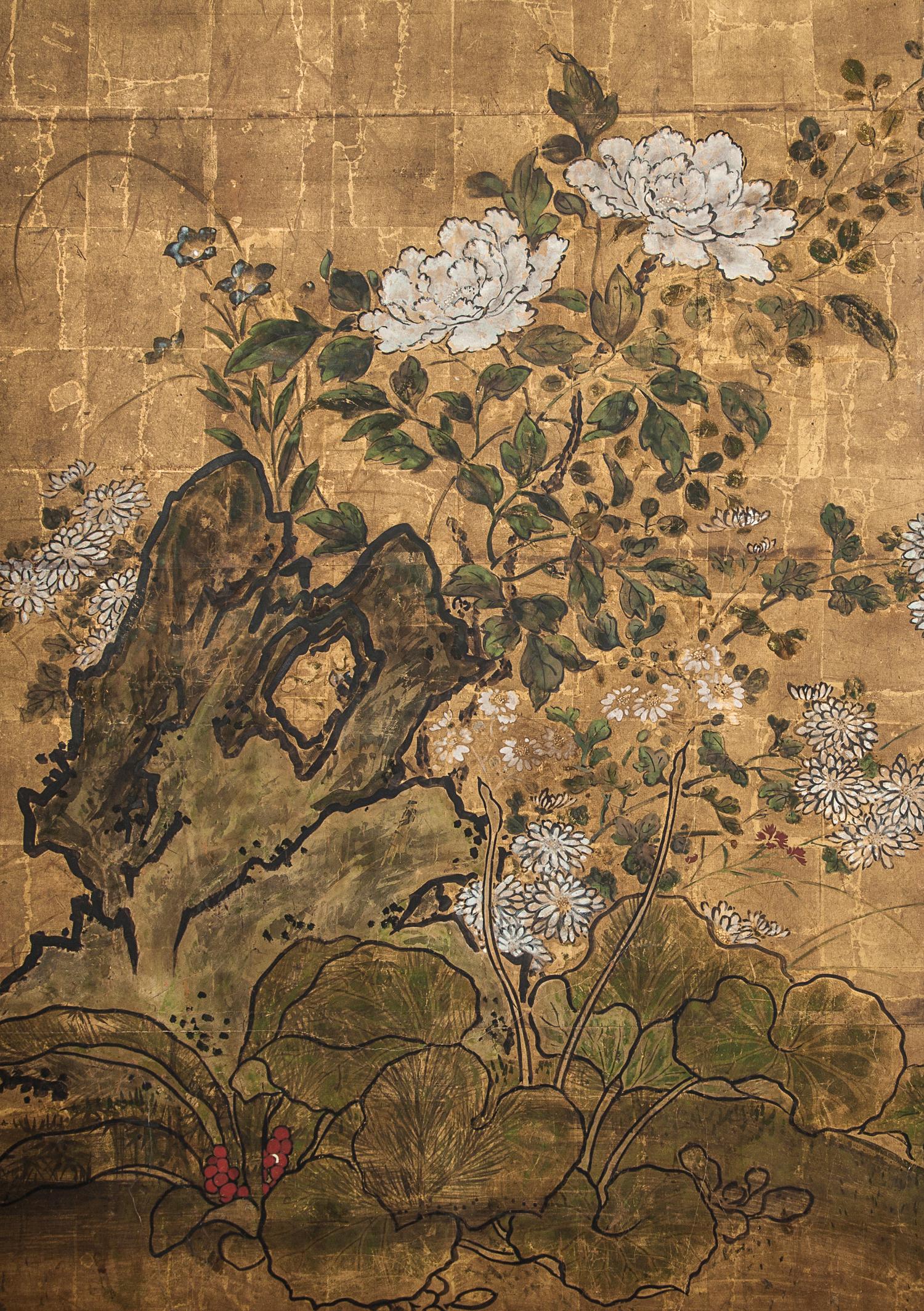 Peonías, caléndulas y rosas junto a una piedra de jardín con suaves picos montañosos al fondo. Pintura del periodo Edo tardío (1603 - 1868) en pigmentos minerales sobre pan de oro con borde de brocado de seda.