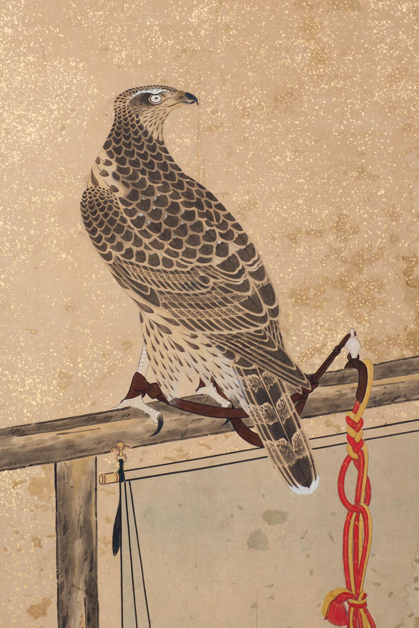 Late Edo period (1614-1868) painting of two falcons with silk knotted tethers resting on perches. Ink on paper mounted on gold with gold flecks, a hand painted checkerboard pattern, and a silk brocade border. Painting is circa 1800, mounted on board