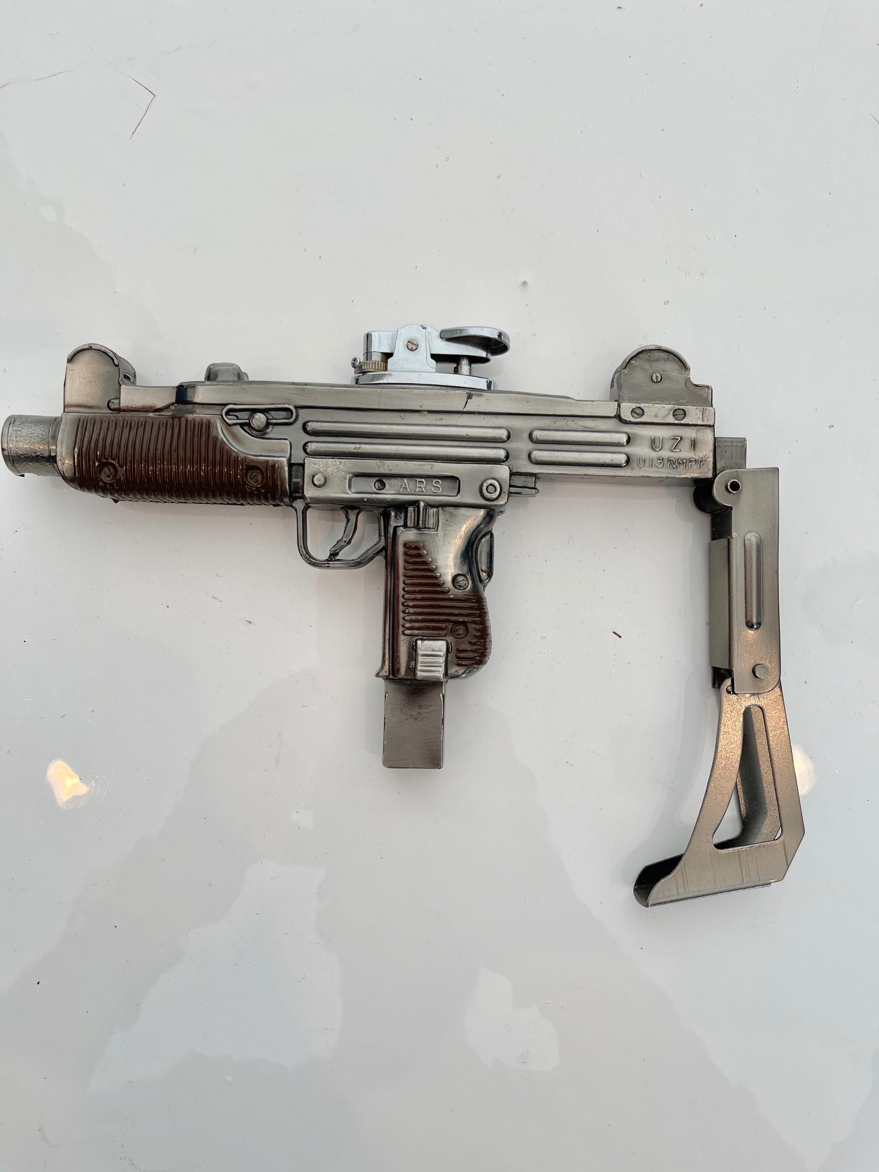 Unique vintage table lighter in the shape of an Uzi. Made in Japan. Working joints on the stock of the Uzi. Damage to end of barrel as shown in photos. Cool tobacco accessory and conversation piece. Working lighter.