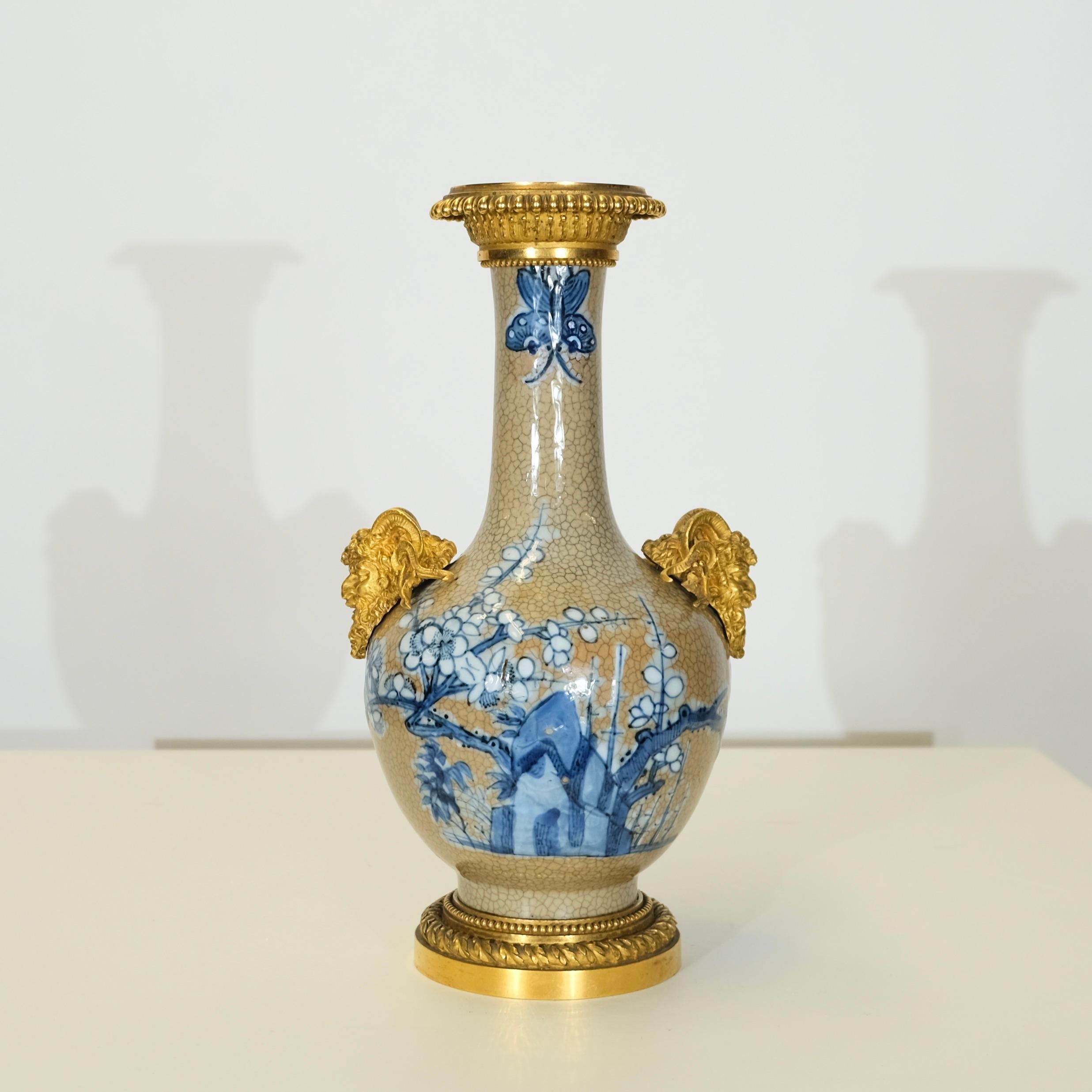 Questo squisito vaso di porcellana giapponese del XIX secolo è una superba miscela di artigianato orientale e opulenza europea. Il corpo è decorato con un delicato smalto blu e beige con intricati motivi floreali e ispirati alla Nature su una