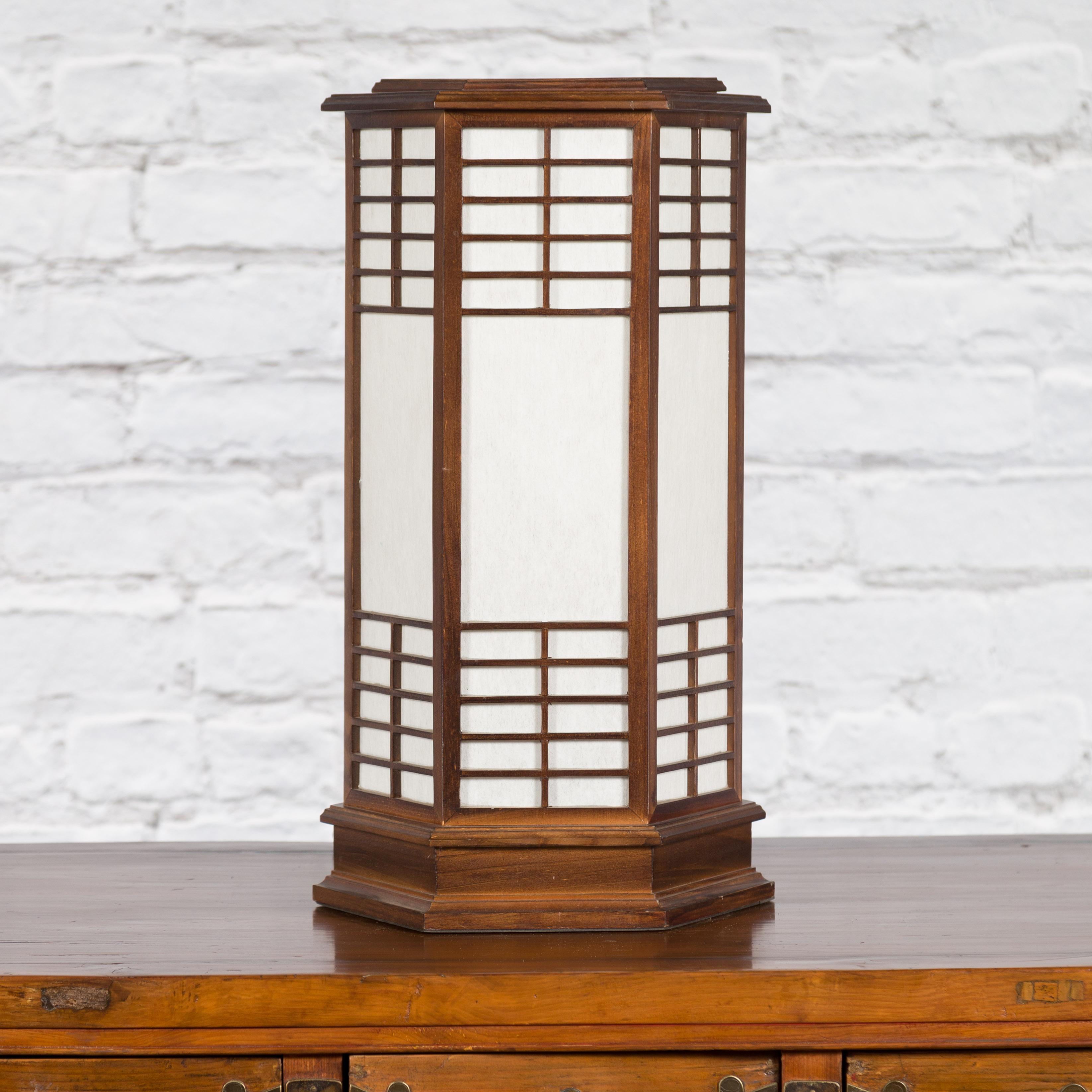 A vintage Japanese hexagonal wooden table lamp from the mid 20th century, with two lights and rice paper. Created in Japan during the midcentury period, this table lamp attracts the attention with its clean lines and complimenting colors. Showcasing