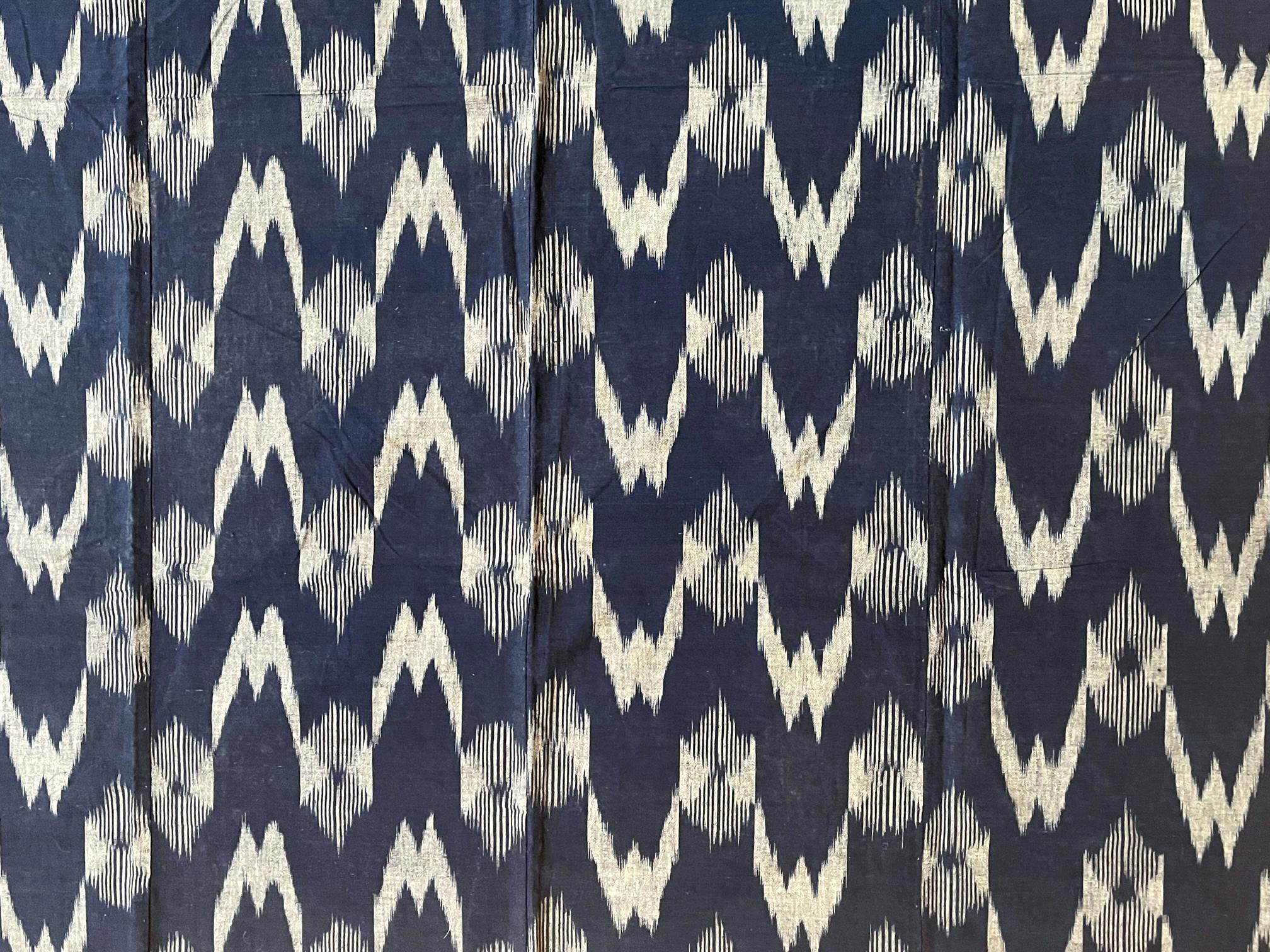A Japanese hand-woven panel with indigo blue background with white ikat chevron and diamond pattern. Sewn together from four loom-woven narrower stripes, the large panel was likely a Futonji (futon cover) or Yutan (covering cloth) based on its size.