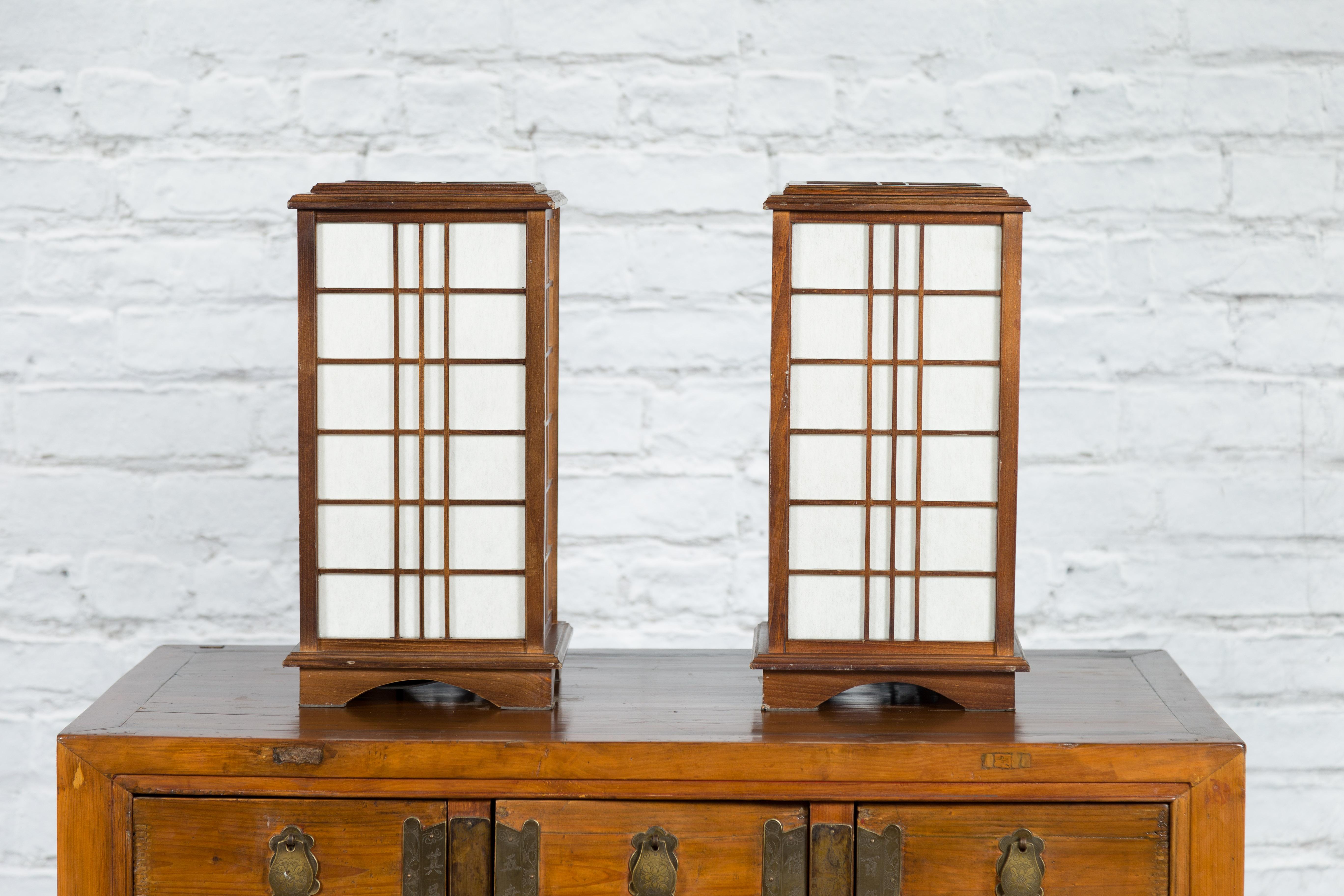 Two vintage Japanese square-shaped wooden table lamps from the mid 20th century, with two light sockets and rice paper panels, priced and sold each individually. Created in Japan during the midcentury period, these vintage table lamps attract the