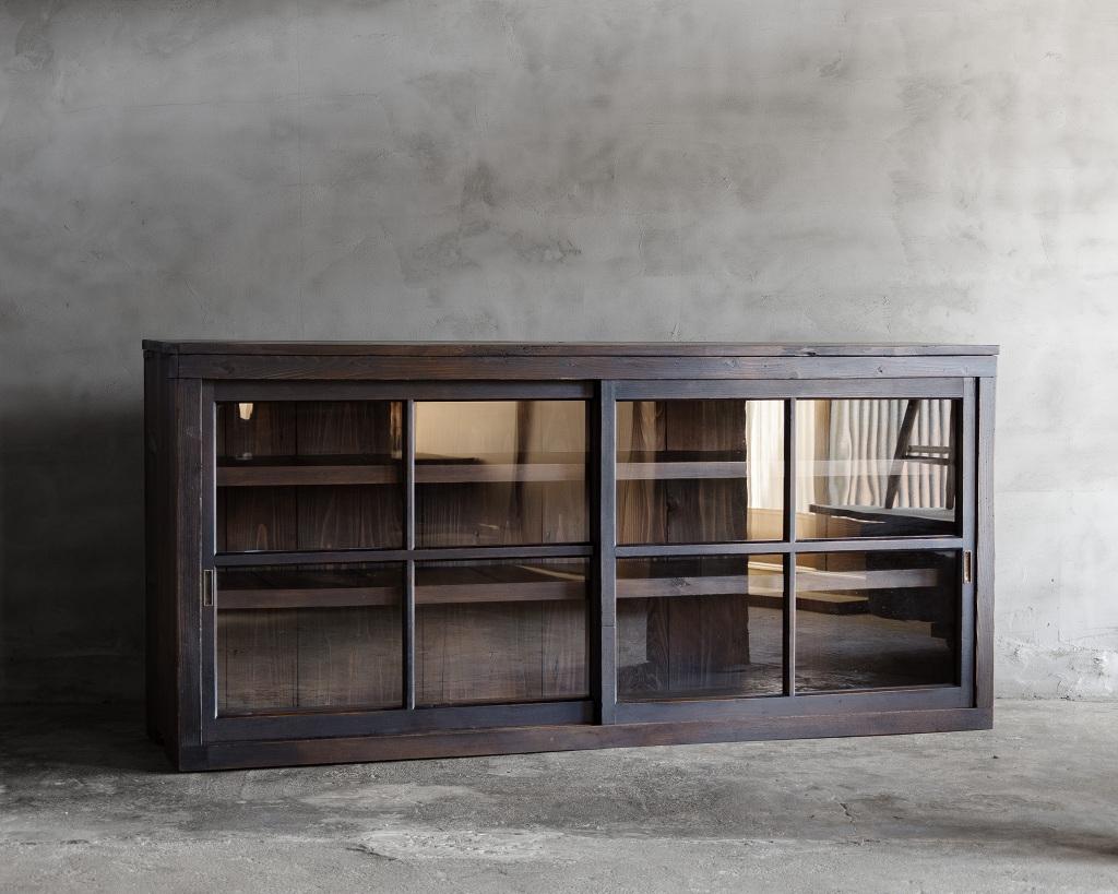 This vintage glass sliding door was crafted in the Mid-Showa Period '1940s-1960s'.

This wide glass sliding door cabinet offers a perfect blend of sophistication and practicality.
Its deep, brownish-black finish adds a refined and tranquil touch to