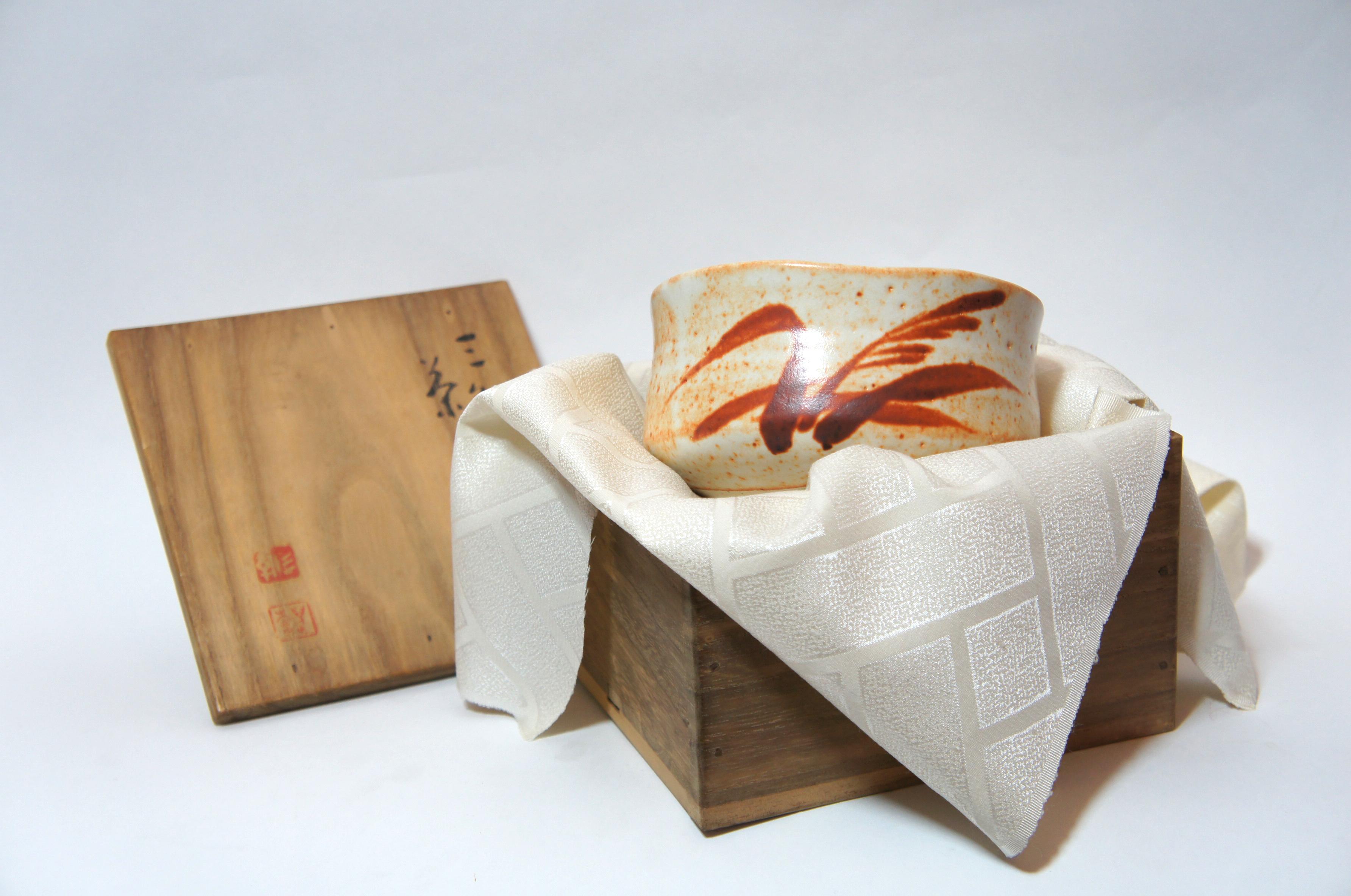 Beautiful Shino ware ceramic tea bowl for the tea ceremony. It is glazed with white and orange.
Shino ware is Japanese pottery, usually stoneware, originally from Mino Province, in present-day Gifu Prefecture, Japan.

With original wooden
