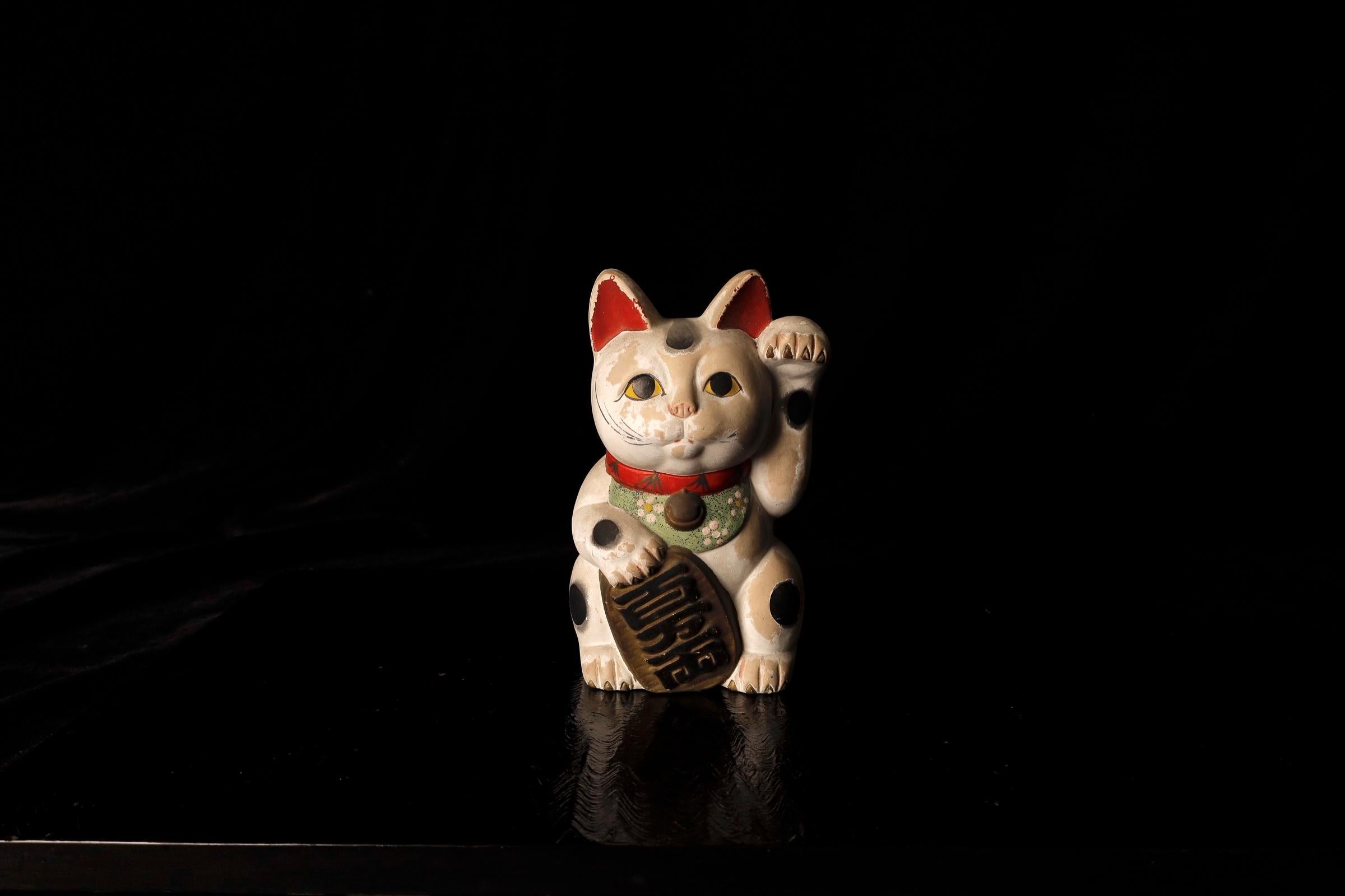 Questo affascinante e raro Maneki Neko (gatto che chiama) dipinto a mano risale al periodo Meiji (1868-1912) e mostra un'eccezionale maestria e attenzione ai dettagli. Conosciuto per il suo gesto simbolico di invito alla fortuna e alla prosperità,