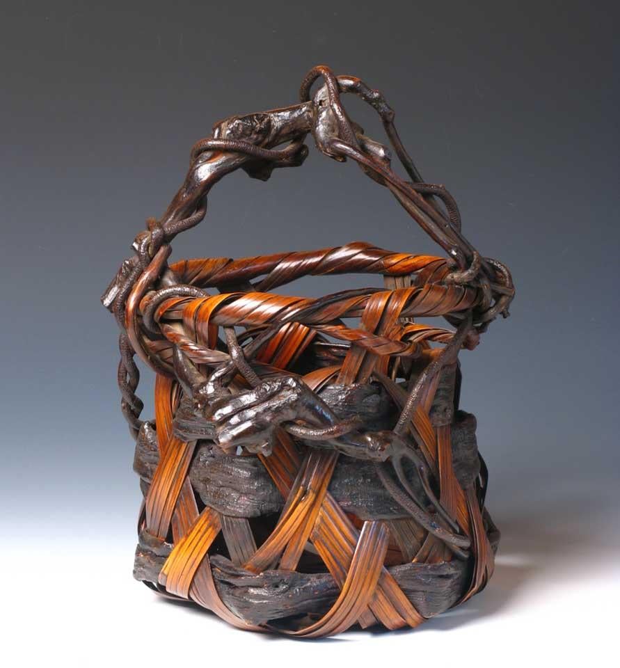 Japanese Wagumi style Ikebana Basket used in the art of flower arranging, woven of horizontal strips of wisteria bark and diagonal strips of bamboo, and overhead assembled wisteria vine handle reaching across the pinched cylindrical bucket form