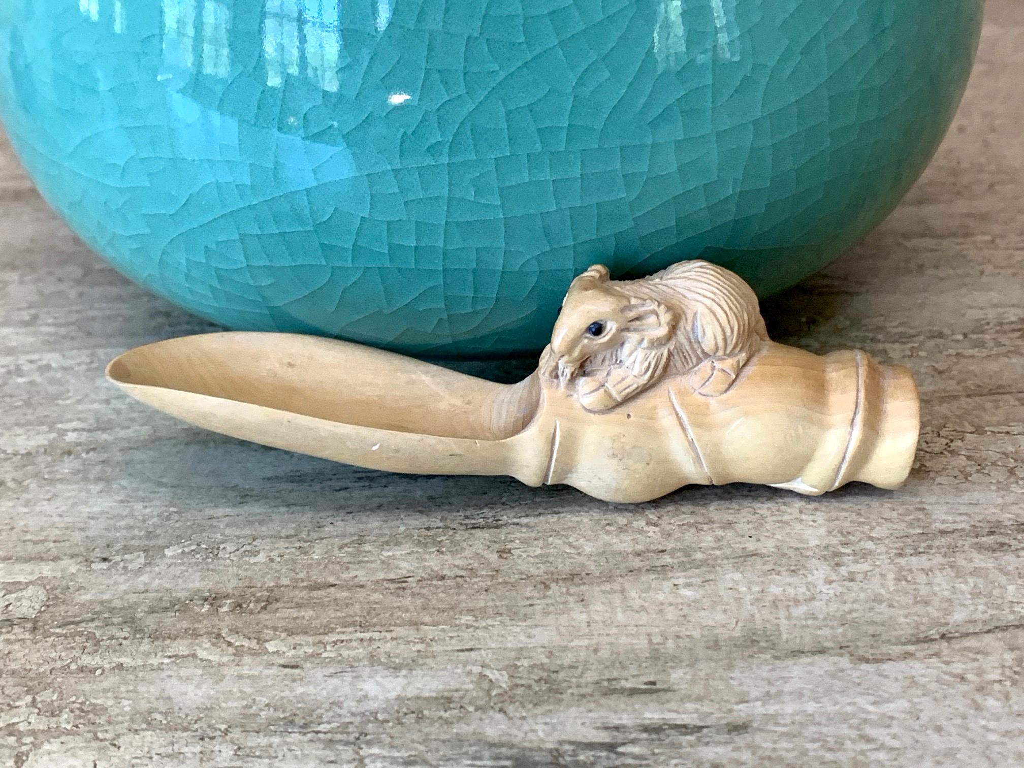 A Japanese netsuke circa first half of 20th century. The whimsical piece was carved out a light-colored wood depicting a small mouse climbing a giant spoon. The rendition is realistic yet at the same time surreal in scale and proportion. The mouse