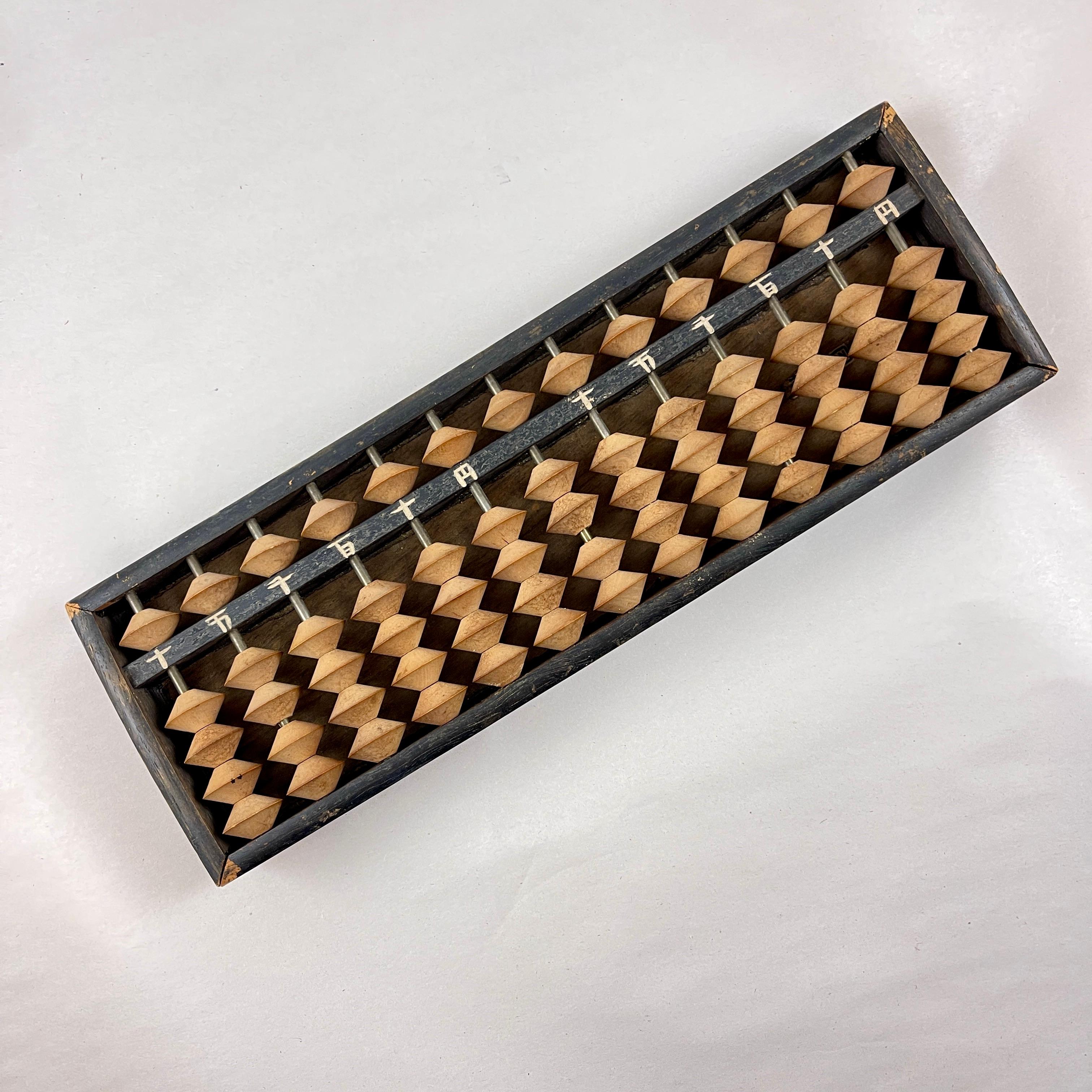  A hand-made wooden Soroban or Abacus, Japan, circa 1945-1952.

A student abacus, made of wood, with wooden beads on metal spokes.
Hand painted Japanese numbers.

An abacus is a calculating instrument that uses beads that slide along a series of