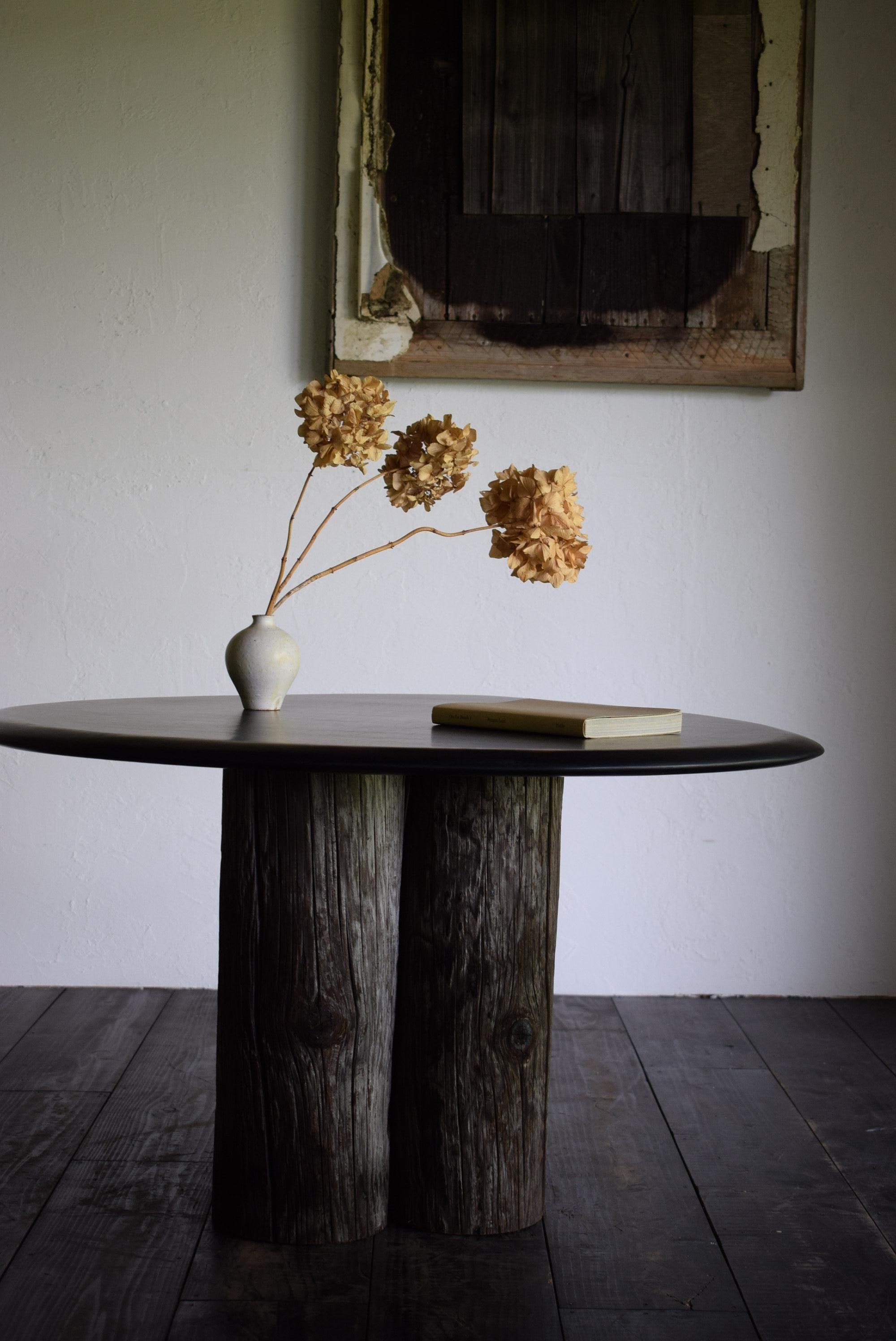 This table is made by combining an old tree stump with a newly made tabletop.
The tabletop is made of a single piece of wood and has a lacquer-like finish. It is black with fine hairlines, giving it a surface that resembles black stone.

The base of