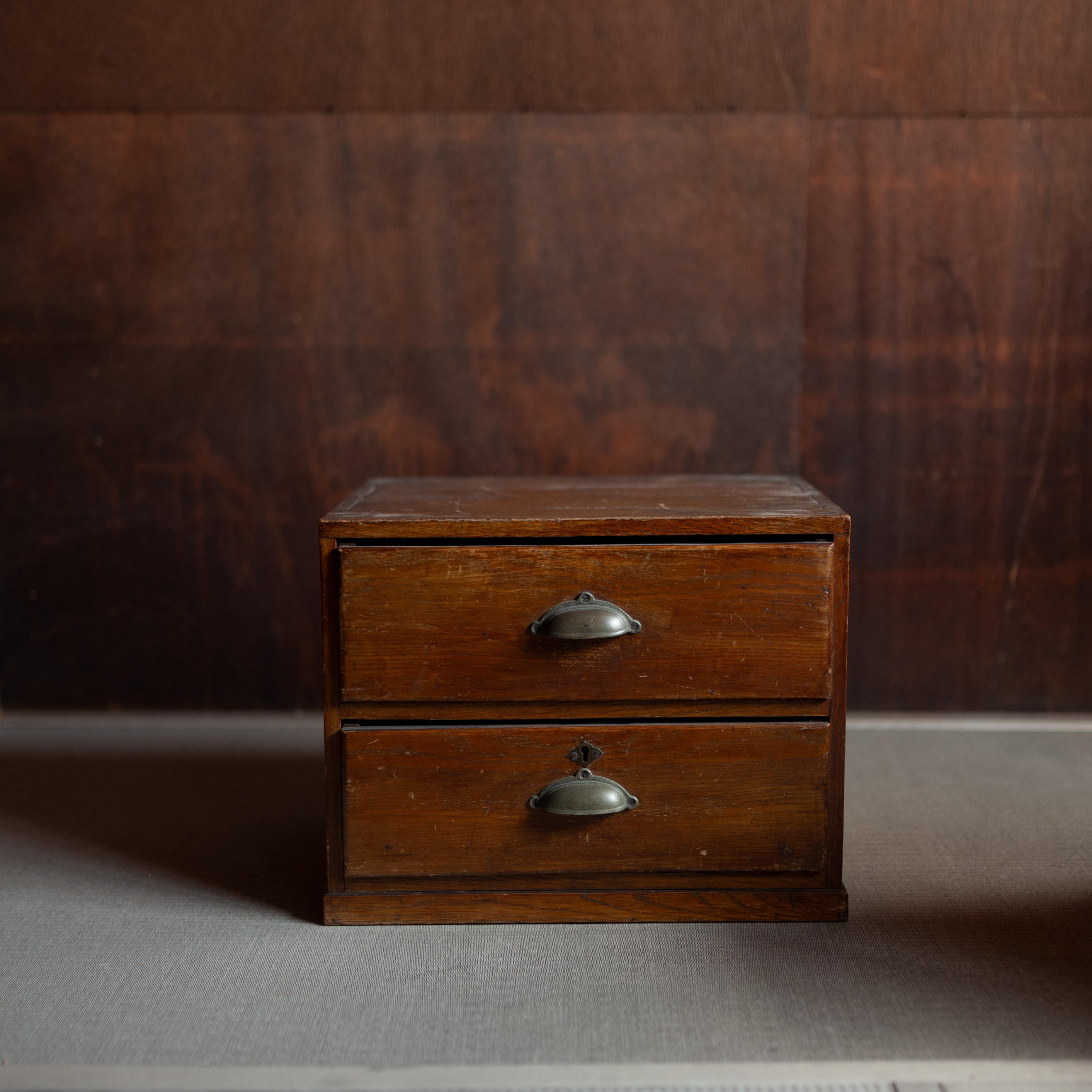 Japanese wooden two-drawer chest.  Modest in scale and design, it reflects the simplicity of Japanese everyday craftsmanship, with clean lines, warm wood grain, and original metal drawer pulls.

While originally intended as a practical storage box