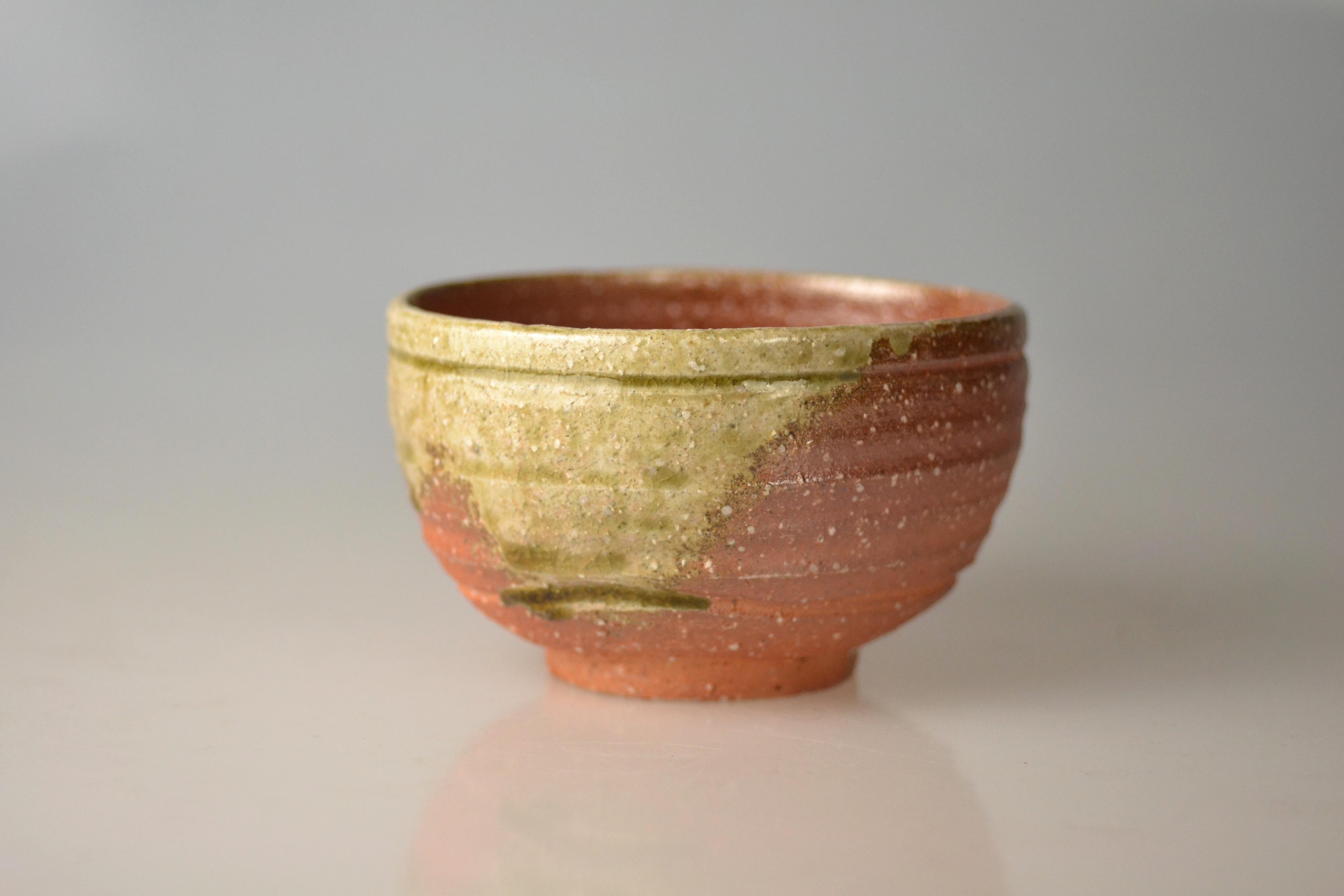 Traditional, hand-thrown tea bowl for matcha with ash glaze from wood firing. Takahashi Rakusai IV (1925) is one of Japan's grand masters of traditional pottery who specialized within his family business on Shigaraki ware. Shigaraki ware is a sandy