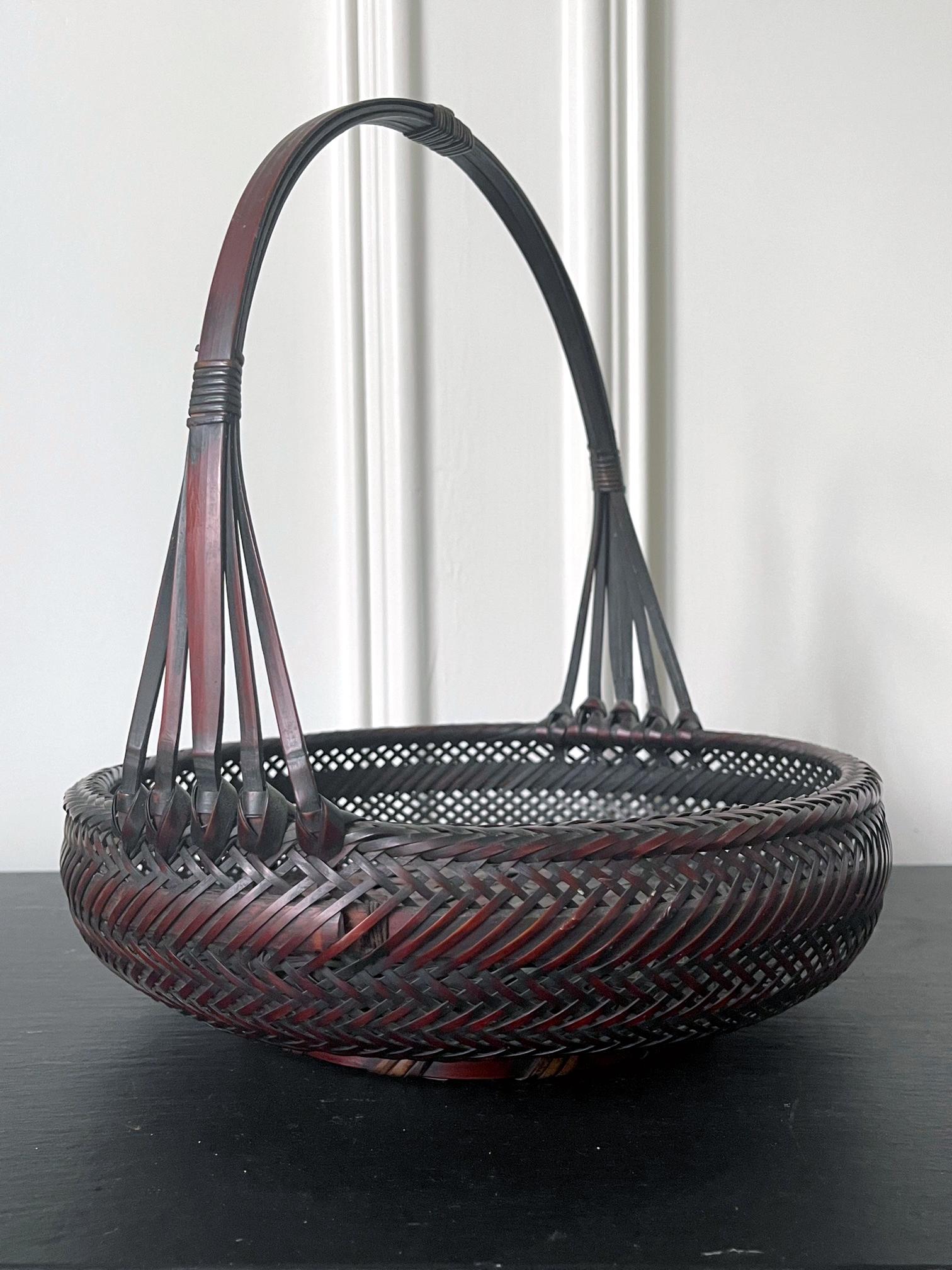 A Japanese woven bamboo basket with handle from early 20th century, circa end of Meiji to Taisho period. The basket was constructed in the form of a morikago. a shallow and open basket with handle. Traditionally, a morikago was used to display