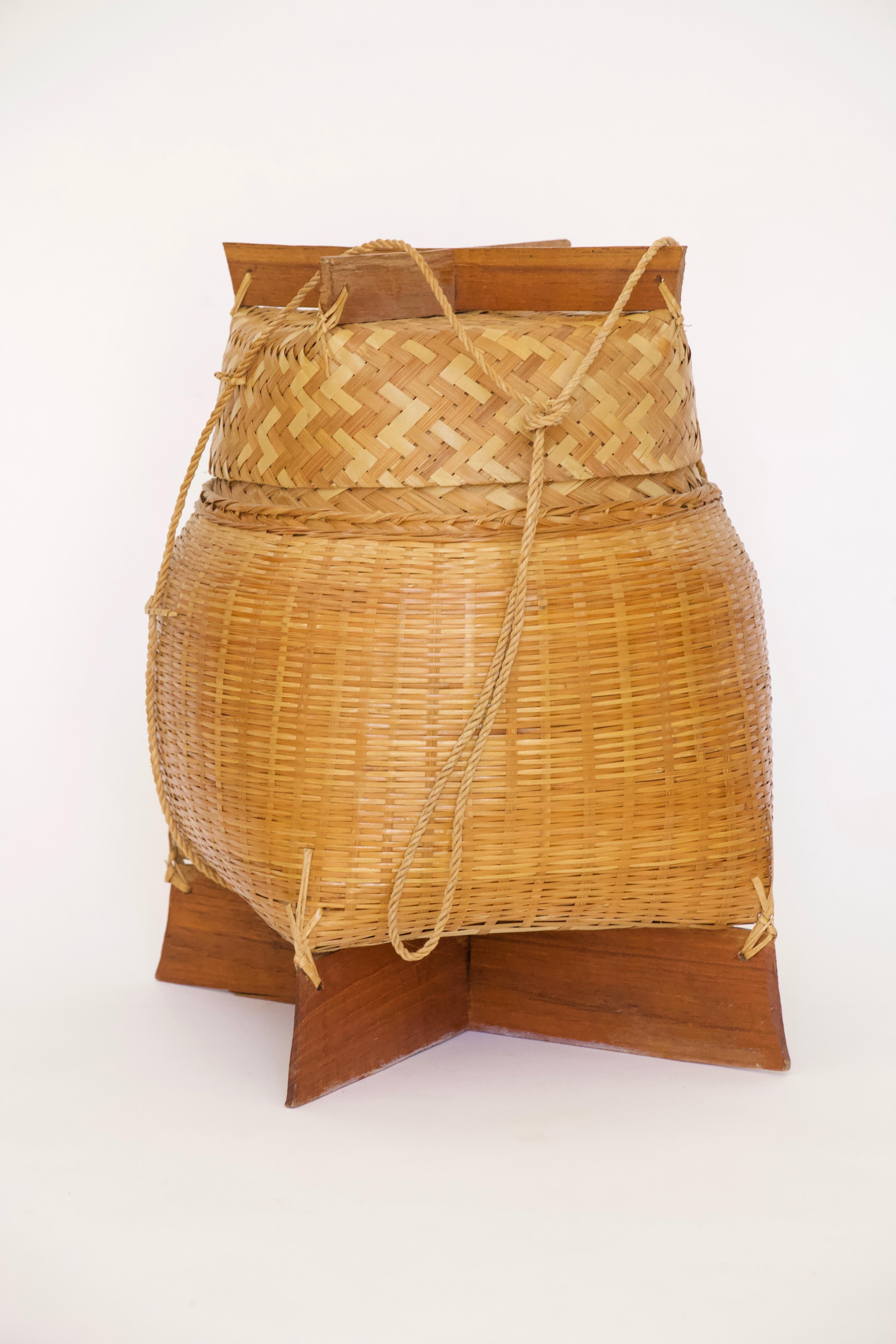 A beautiful Asian woven decorative bamboo basket with lid and cord handle. A wonderful decorative storage option and conversation piece.