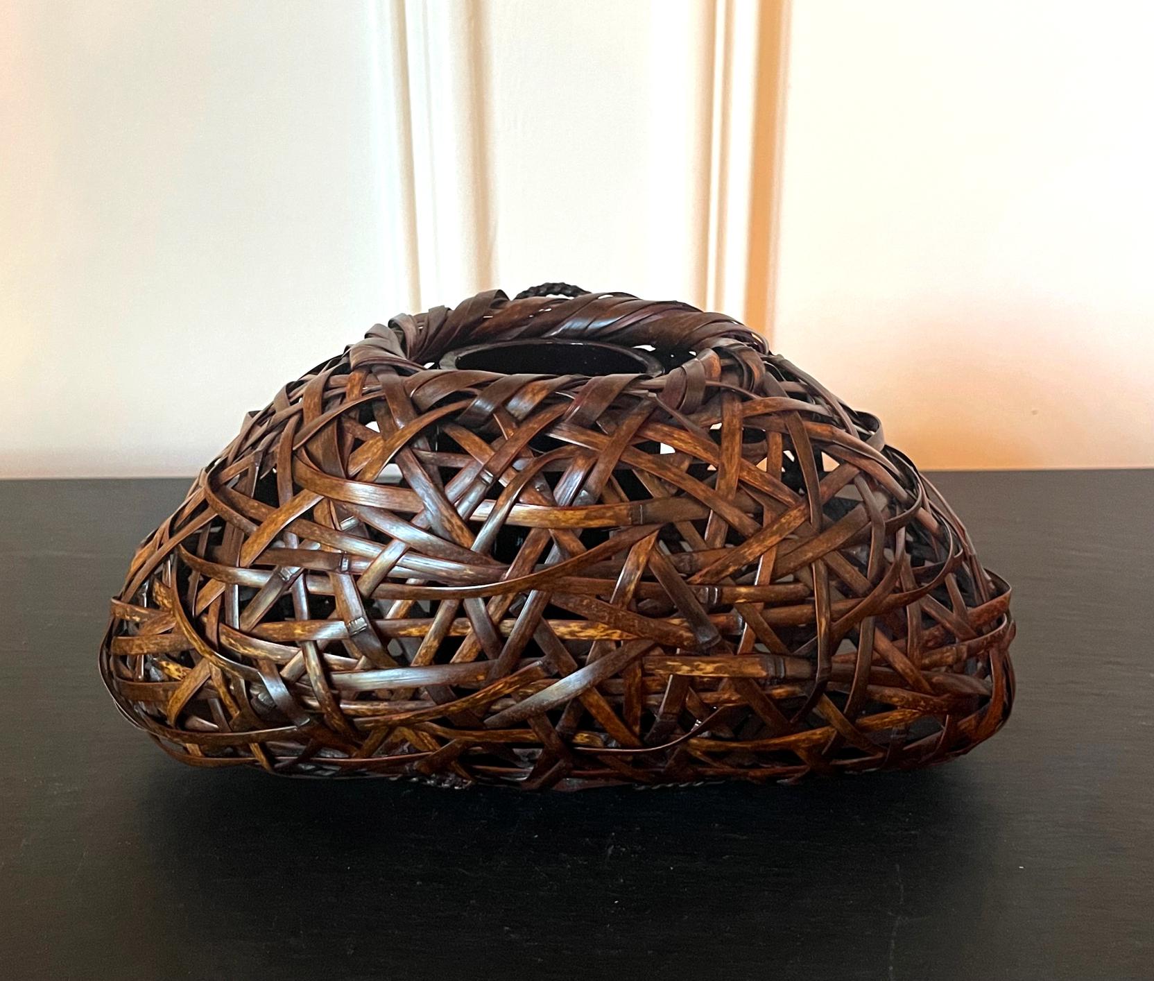Un Hanakago en bambou éveillé japonais, un panier Ikebana suspendu au mur par Suemura Shobun (1917-2000). Le panier est intitulé Purple Bamboo Mt. Fuji et a été tissé avec du Susudake (bambou fumé) en utilisant une technique de tressage irrégulière
