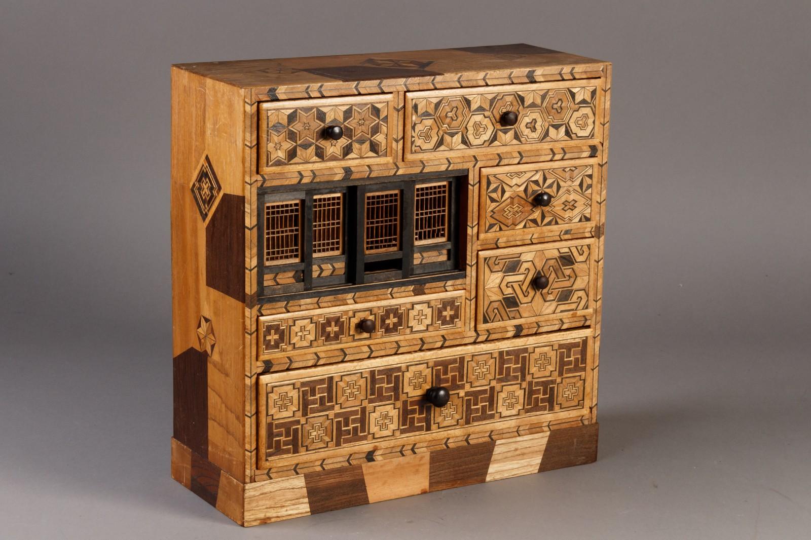 Charming table-top Japanese Yosegi (Yosegi-zaiku) jewelry box made of wood with Japanese decoration in black and inlaid designs of different woods, the  front with 6 drawers and 4 small sliding doors, Meiji period, early 20th C.
   