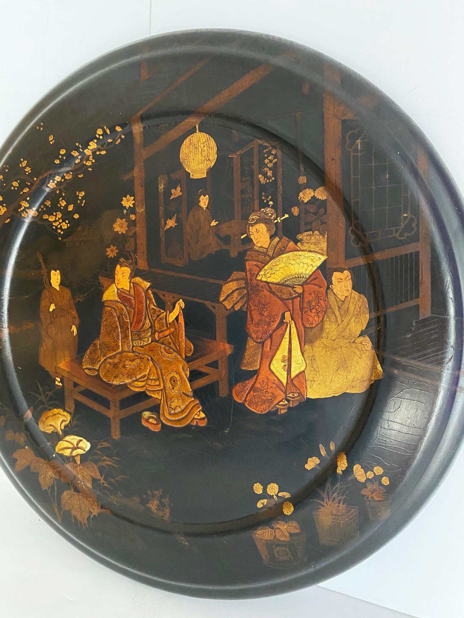  A Japanese Papier Mache Decorative Charger (plate).  Classic Japanese scenes of people in traditional dress.  The bottom edge is missing black lacquer.
