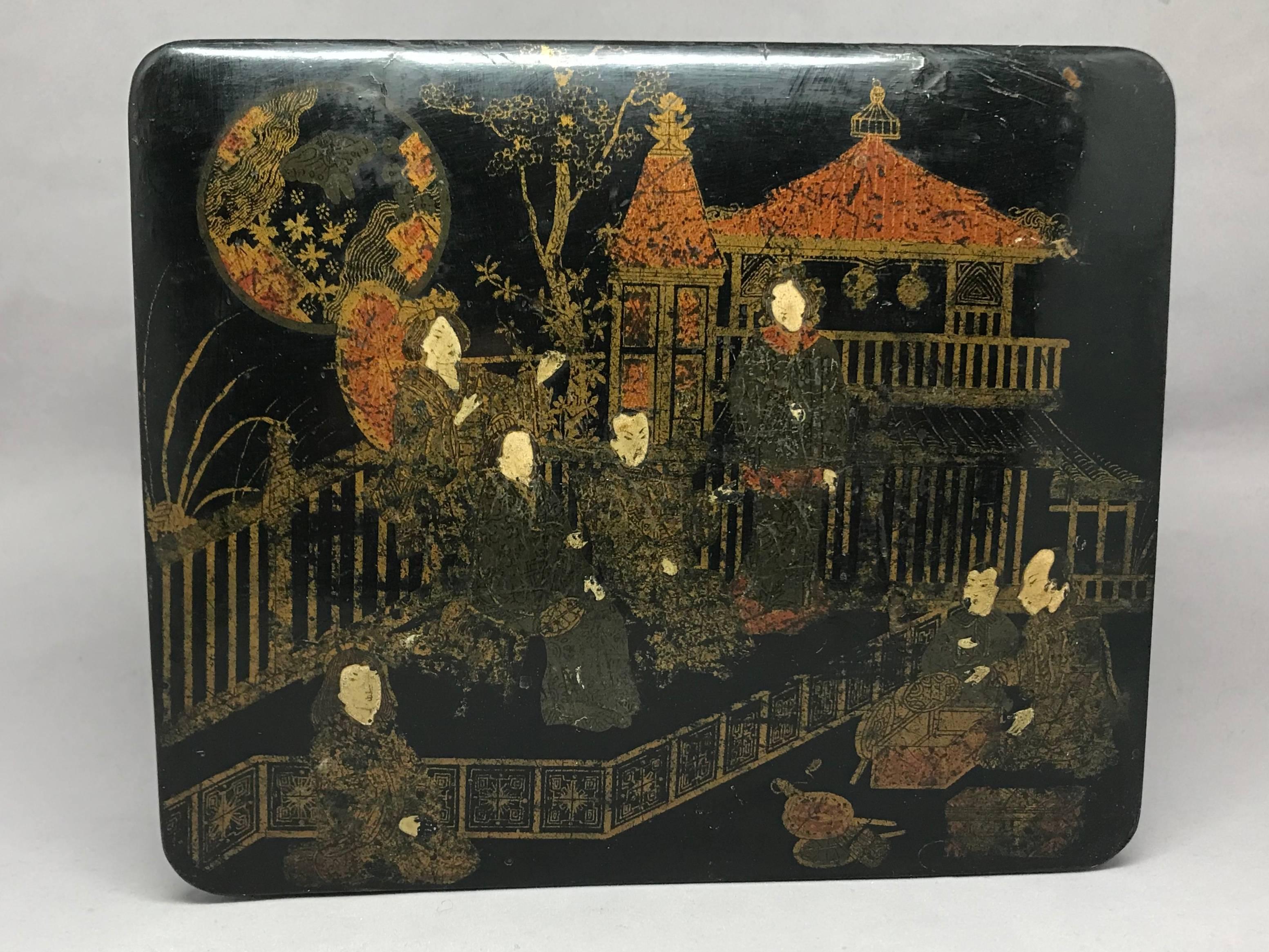 Japanned black lacquer box. An English red and gilt finely hand-painted black lacquer lidded box with oriental nobility in a fenced garden landscape with pagoda-ed structures and full moon, opening to a red painted interior. England, mid-19th