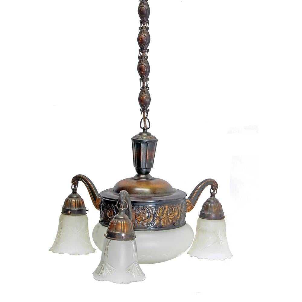 Salvaged from the no longer extant Lloyd Golf Course Clubhouse in Portland, or this beautiful three pendant domed pan style chandelier has a stamped rose motif with a japanned finish. It also features a lovely medallion style chain and frosted