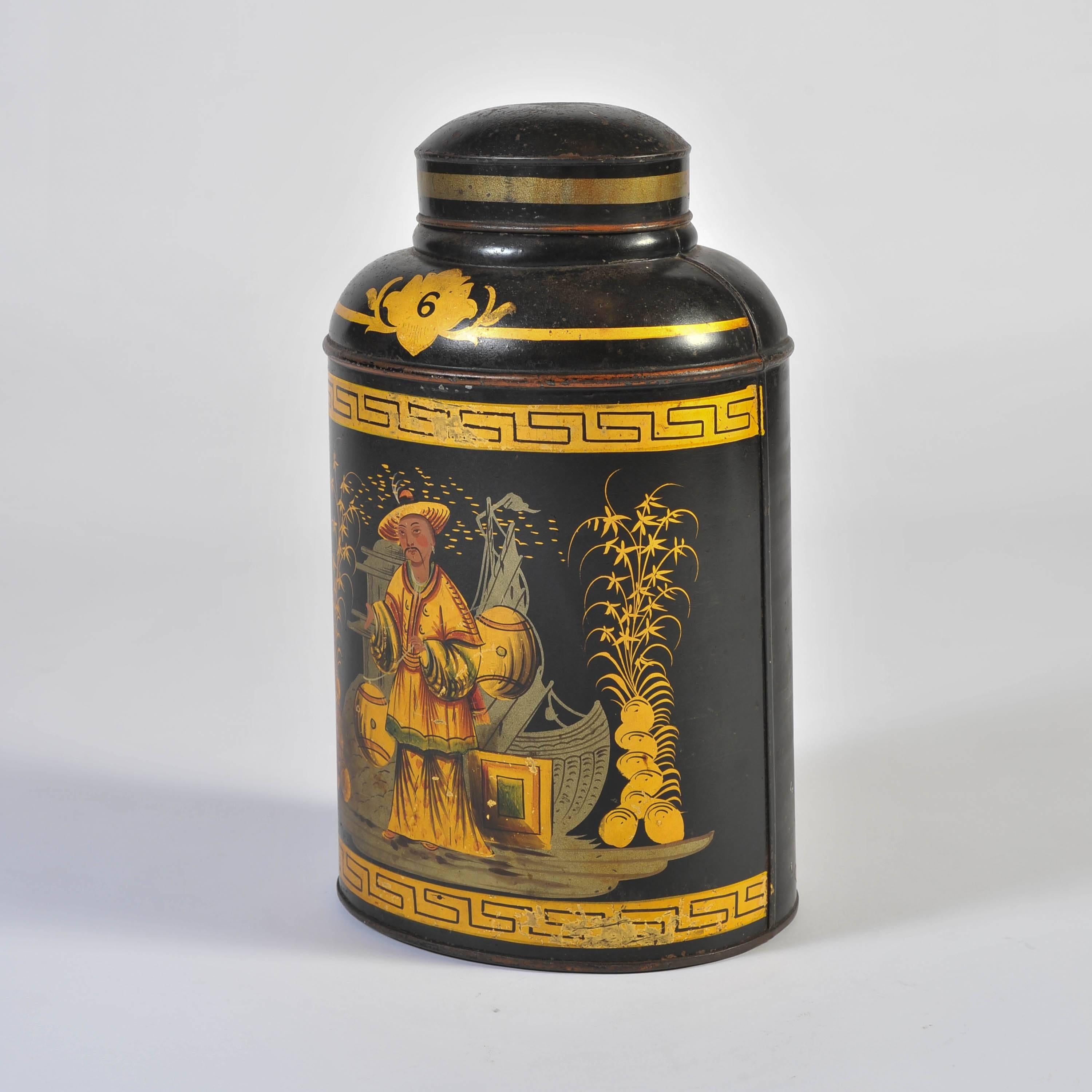 Numbered 6, this lidded oval canister painted and decorated to depict a Chinese figure with trading goods in front of a ship all within a Greek key pattern border.
An oval label to the reverse: 