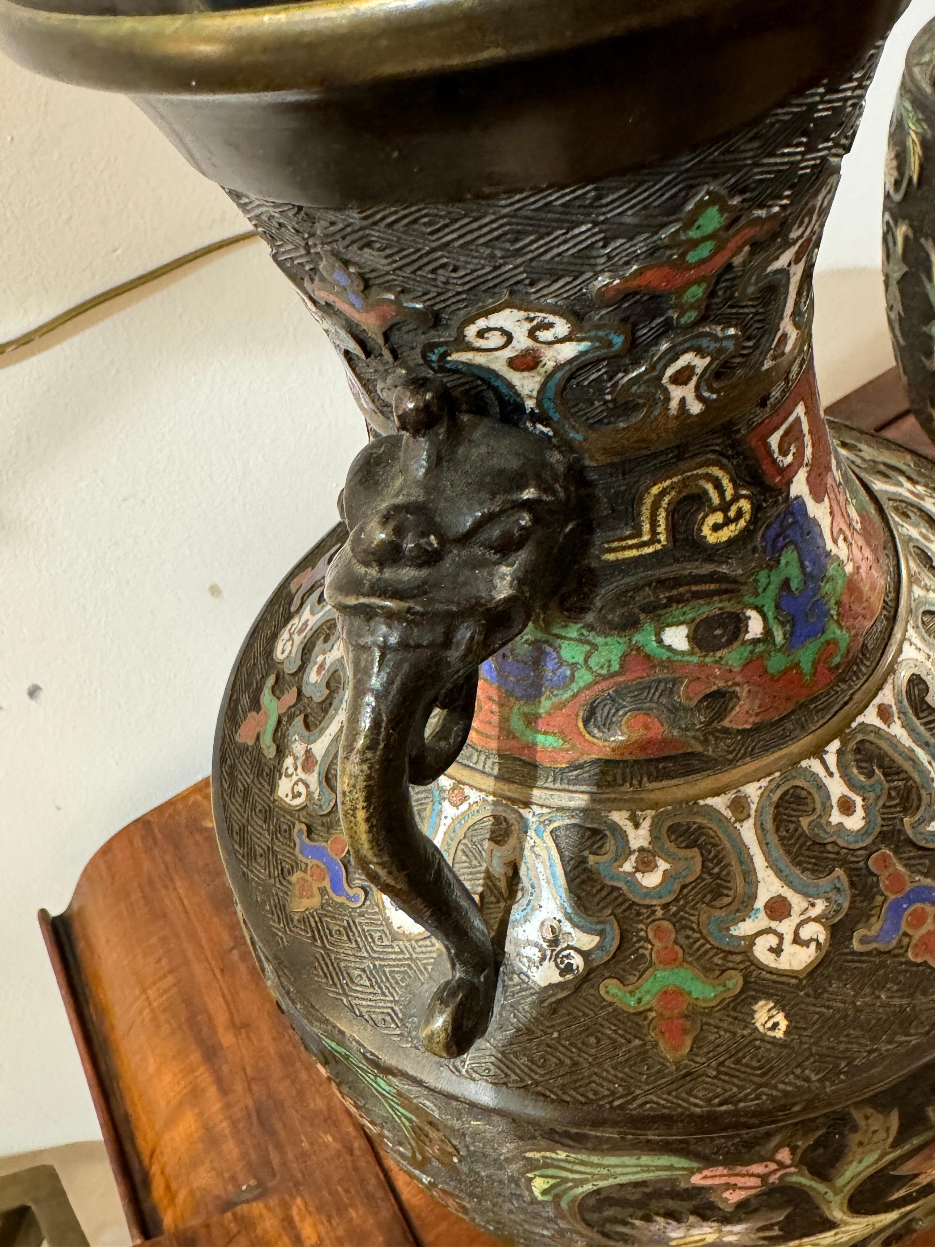 GIAPPONE - Epoca MEIJI (1868-1912) Coppia di vasi con balaustre a colonnina e due anse a forma di têtes de chimères, in bronzo e pietre cloisonnés con decori a base di motivi geometrici.
 Dimensioni 52 cm
 diametro della base 18 cm 
 diametro più