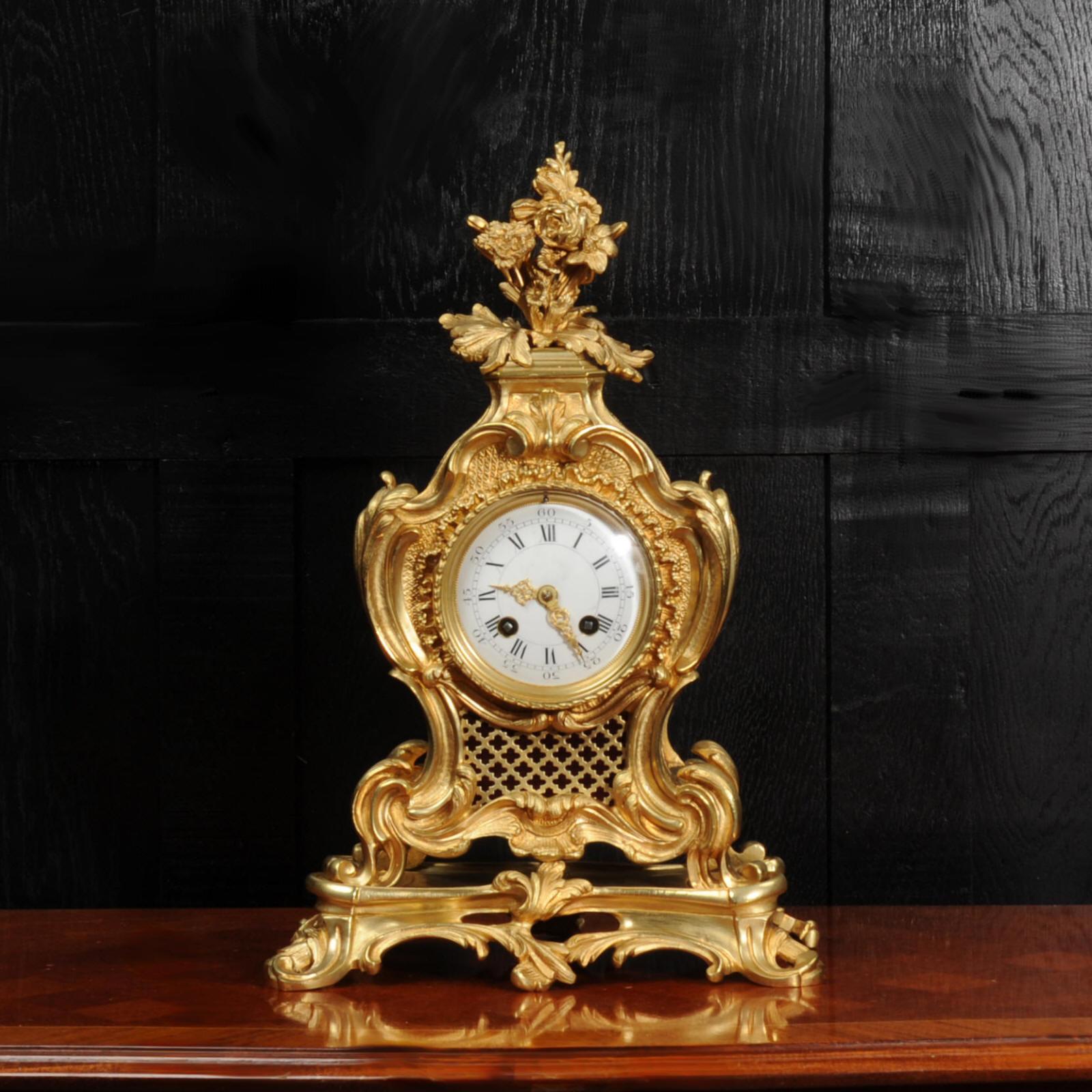 A stunning original antique French Rococo clock by Japy Frères. It is beautifully sculptured with finely finished scrolls, curves and acanthus leaves in finely gilded bronze. To the top is a Rococo flourish of flowers and foliage. Panels backed with