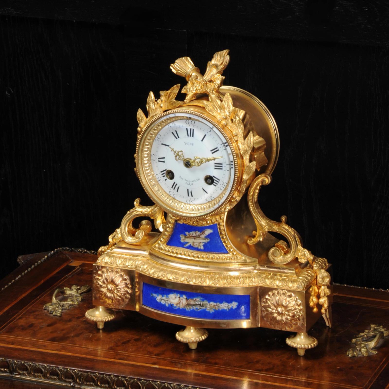 A beautiful and early antique French clock by the famous maker Japy Freres, circa 1860. It is modelled in ormolu (finely gilded bronze), mounted with beautiful porcelain with a blue ground decorated with flaming torche, quiver of arrows and a pair