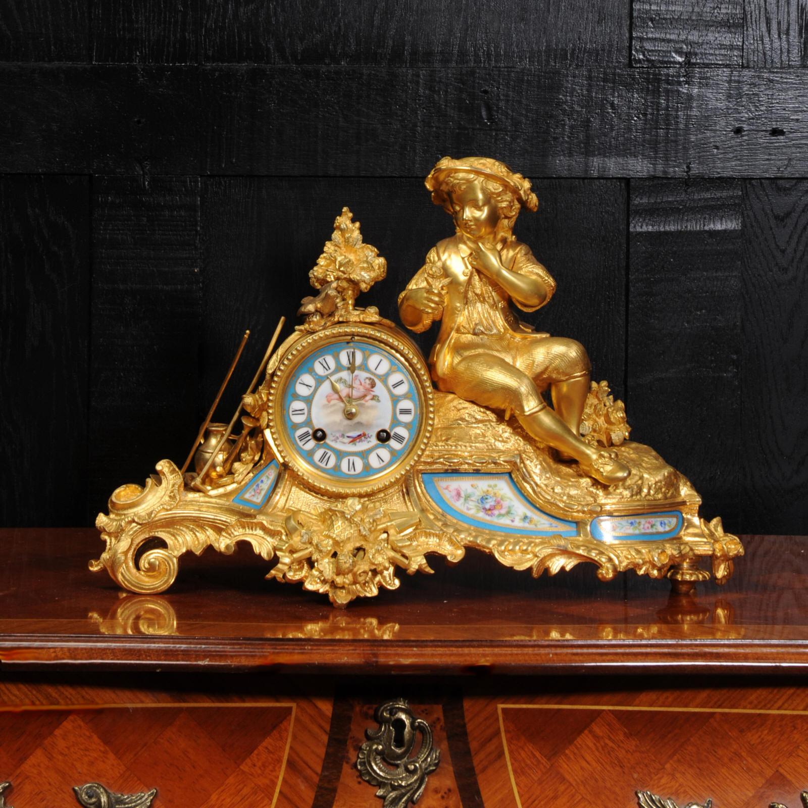A beautiful and early antique French clock depicting a gardener taking a moment's rest with a song bird to his side. It is finely modelled in ormolu (finely gilded bronze) and is mounted with exquisite Sèvres style porcelain. These have delicately