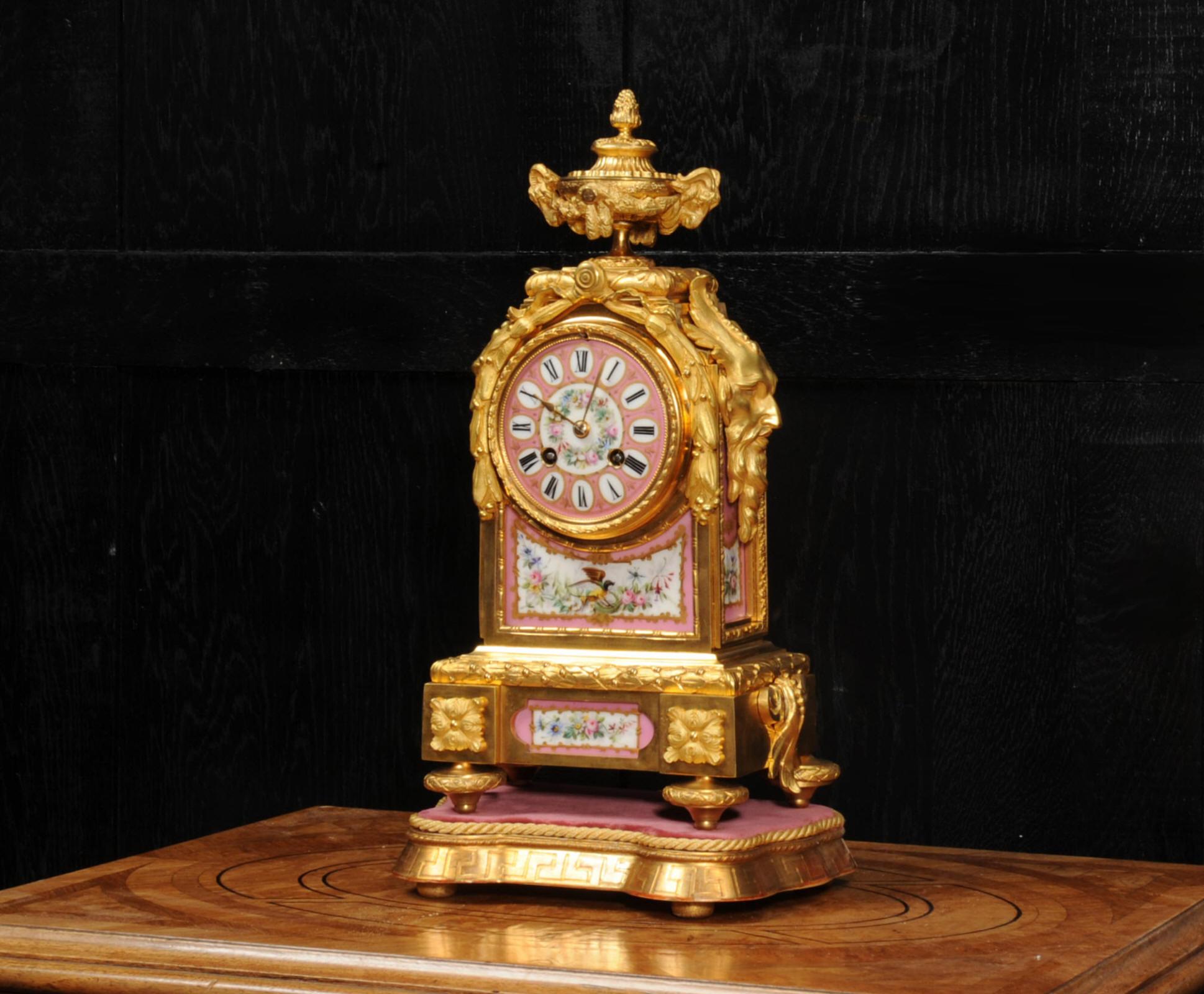 A beautiful ormolu clock, mounted with exquisite panels of Sèvres style porcelain with a pompadour rose ground. Each piece is finely decorated, flowers, an exotic bird and a dragon fly. It is by Japy Frères and was retailed by the well-known London