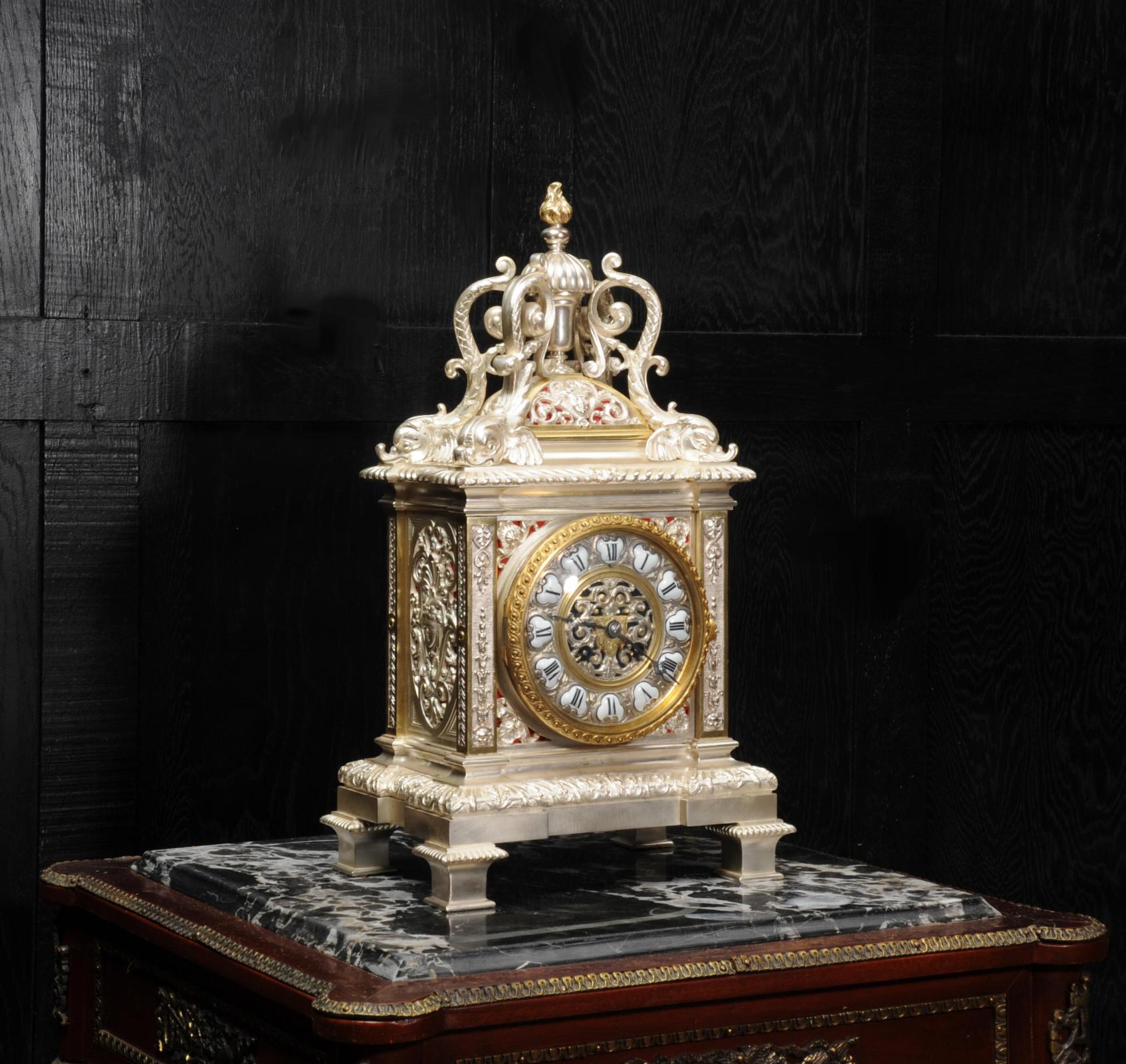 A beautiful and unusual bronze bracket clock, Baroque in style and silver plated with contrasting gild. It is profusely decorated with fabric backed fretted panels with goddess masks, cornucopia and stylised acanthus. To the top are four beautifully