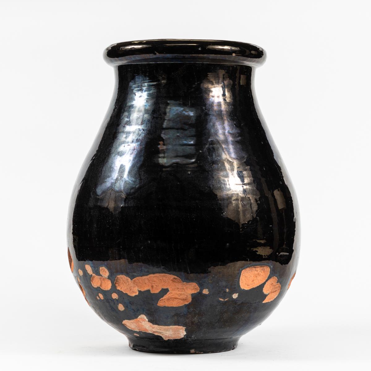 This manufacturing process of this glazed terra cotta jar from 1940s France has given it a truly one of a kind appearance. The upper portion of the vessel has been covered in a thick black glaze.  The lower portion has been chipped away to reveal