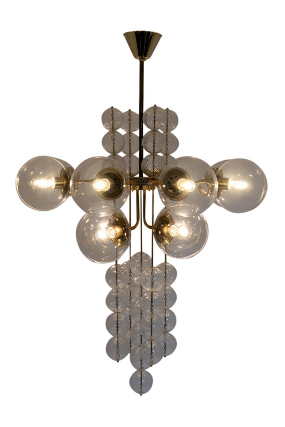 Large chandelier – or suspension – decorated with spheres, with ten arms of light. Blown glass balls, transparent for the ten light arms and with a grid decoration for the decorative ones. Gilded brass frame.

Czechoslovakian work realized in the