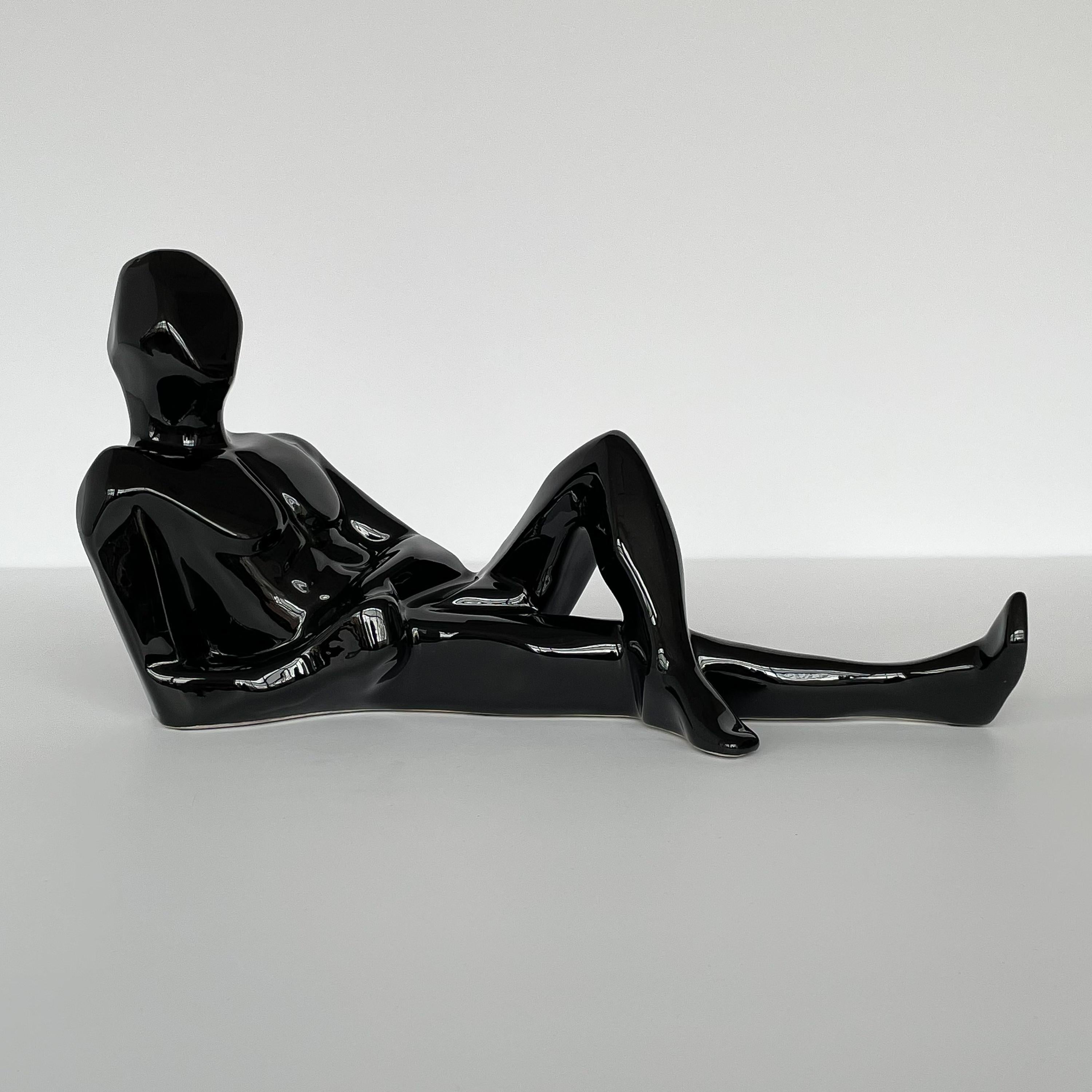 A modernist black glazed figurative ceramic male nude sculpture by Jaru of California, circa 1977. The sculpture depicts a reclining man in repose in an abstract form with a nod to Cubism. Signed and dated 