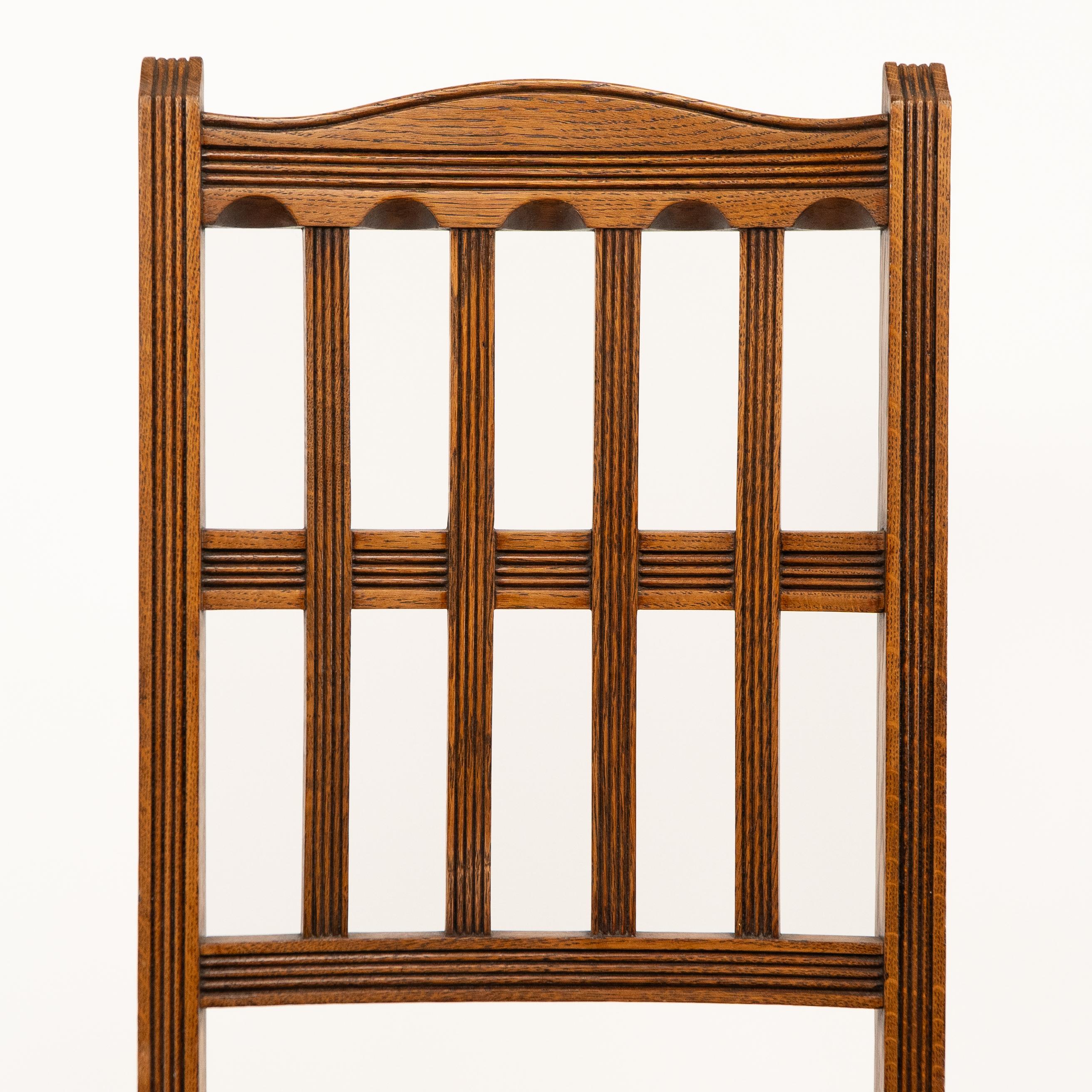 Late 19th Century Jas Shoolbred. A set of four Aesthetic Movement lattice back oak dining chairs