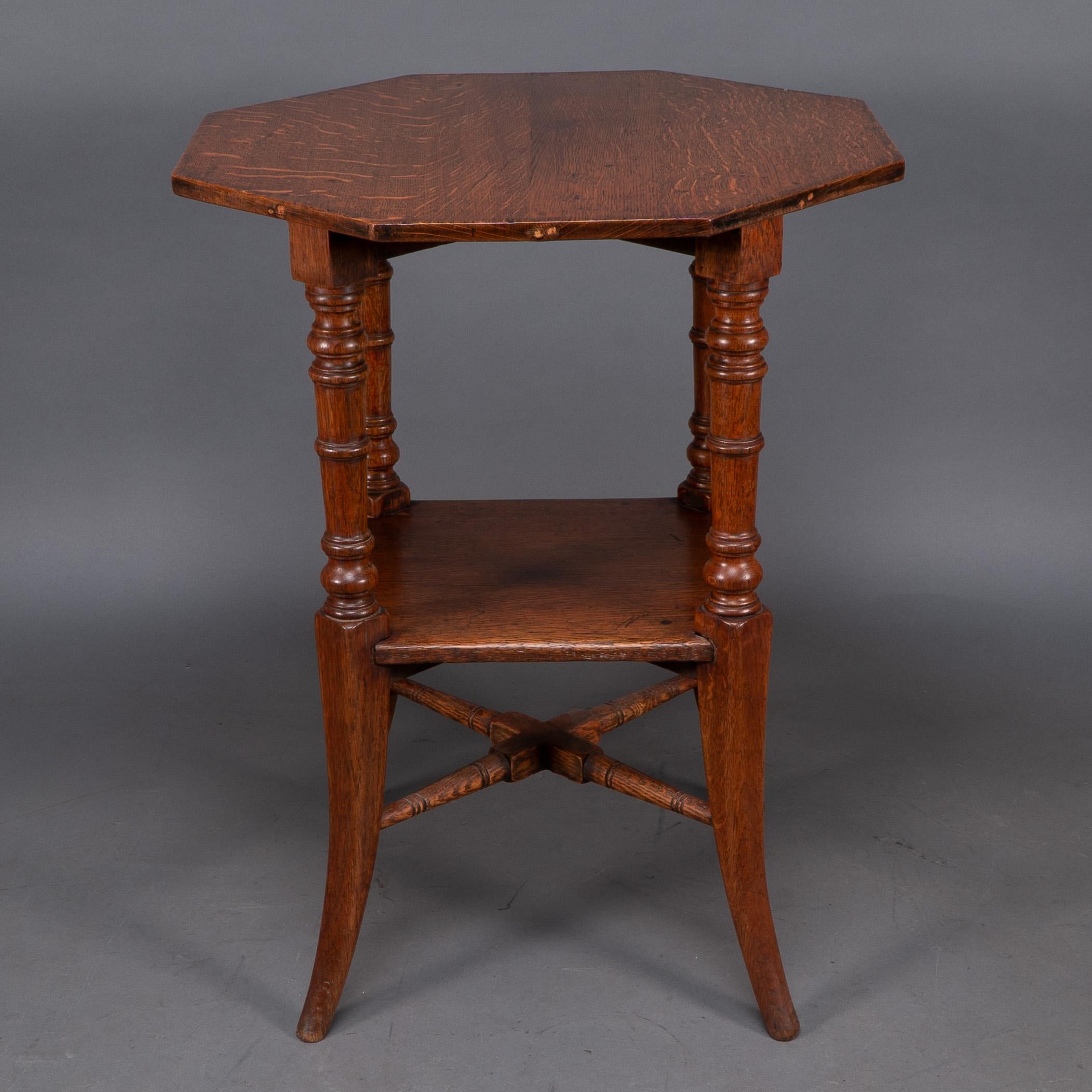 Jas Shoolbred attributed An octagonal oak side table with central shelf, carved circular details to the legs, united by lower cross stretchers.