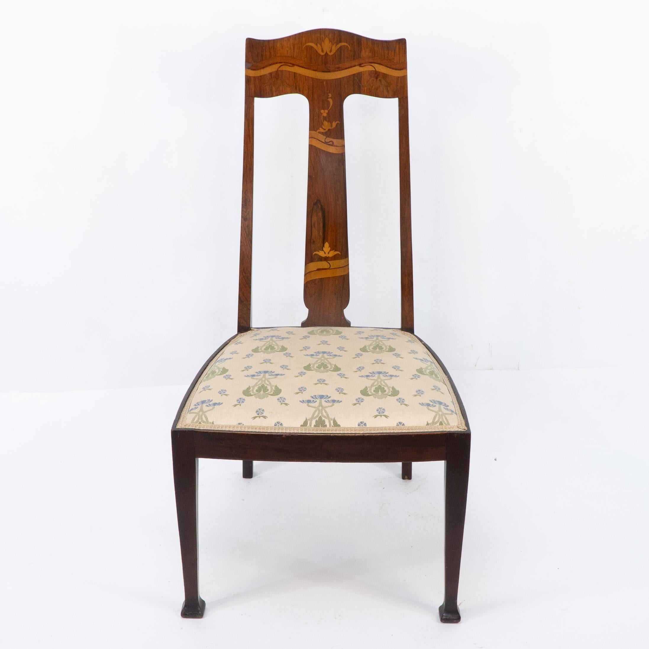 An Arts and Crafts Mahogany and Rosewood nursing chair made by Jas Shoolbred with stylised floral inlaid details to the back and head rest. Original label to the underneath.