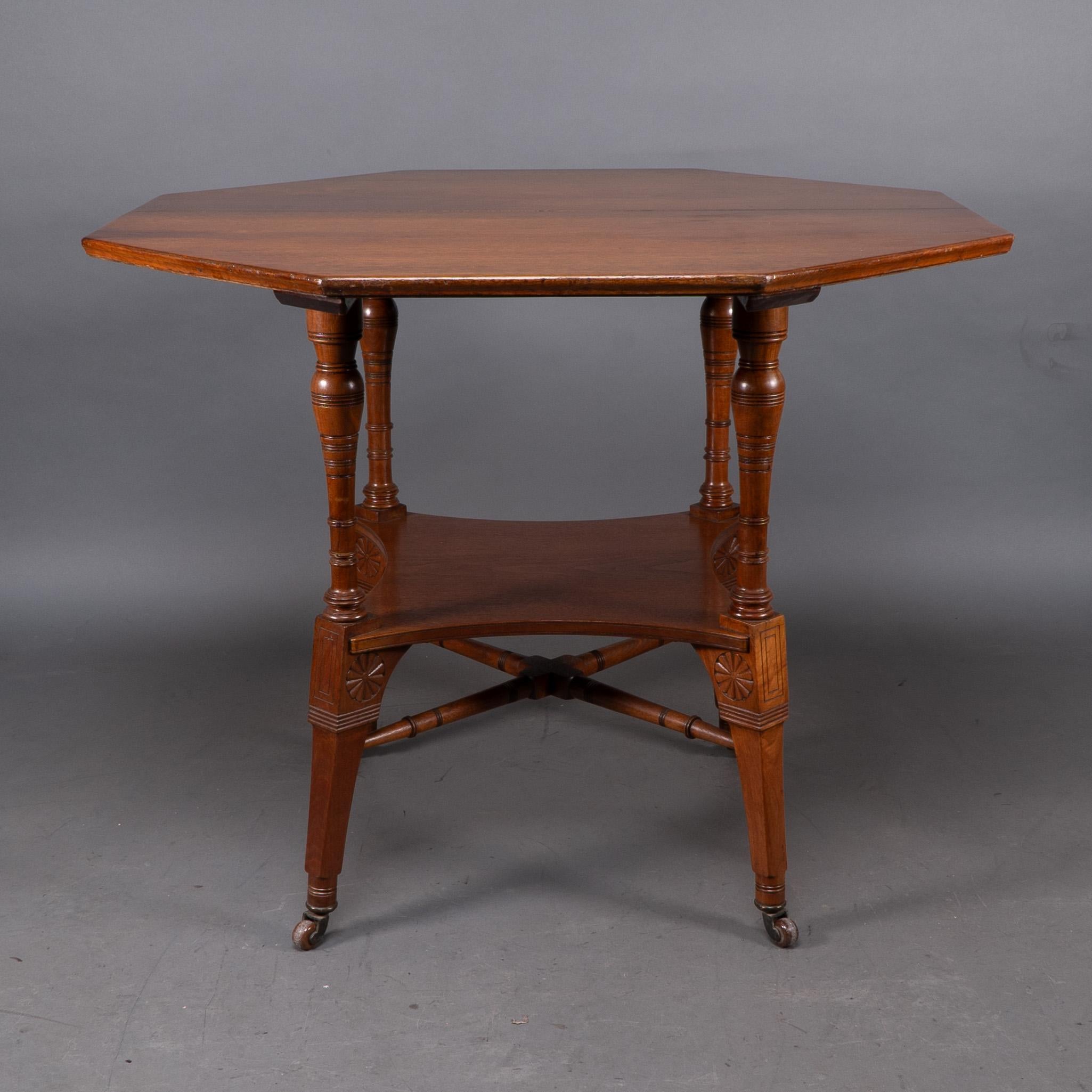 Jas Shoolbred attributed An octagonal Walnut centre table with central shelf, carved circular details to the legs, united by lower cross stretchers.