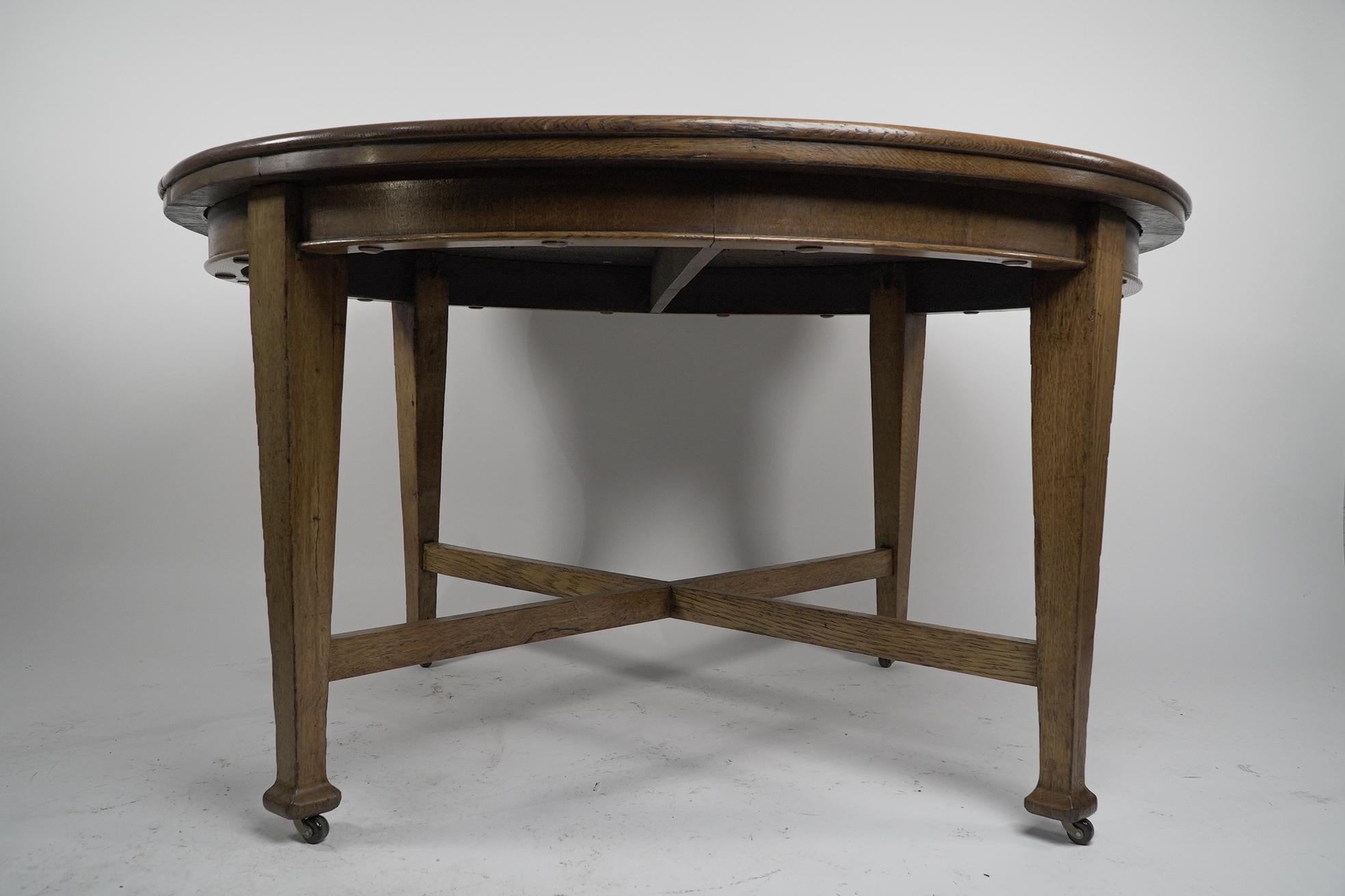 Oak Jas Shoolbred. An Arts & Crafts round oak dining table with square tapering legs For Sale