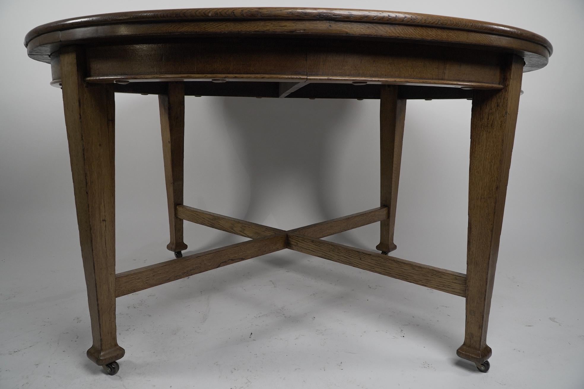 Early 20th Century Jas Shoolbred. An Arts & Crafts round oak dining table with square tapering legs For Sale