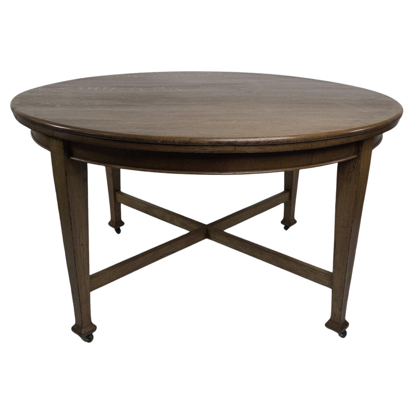 Jas Shoolbred. An Arts & Crafts round oak dining table with square tapering legs For Sale