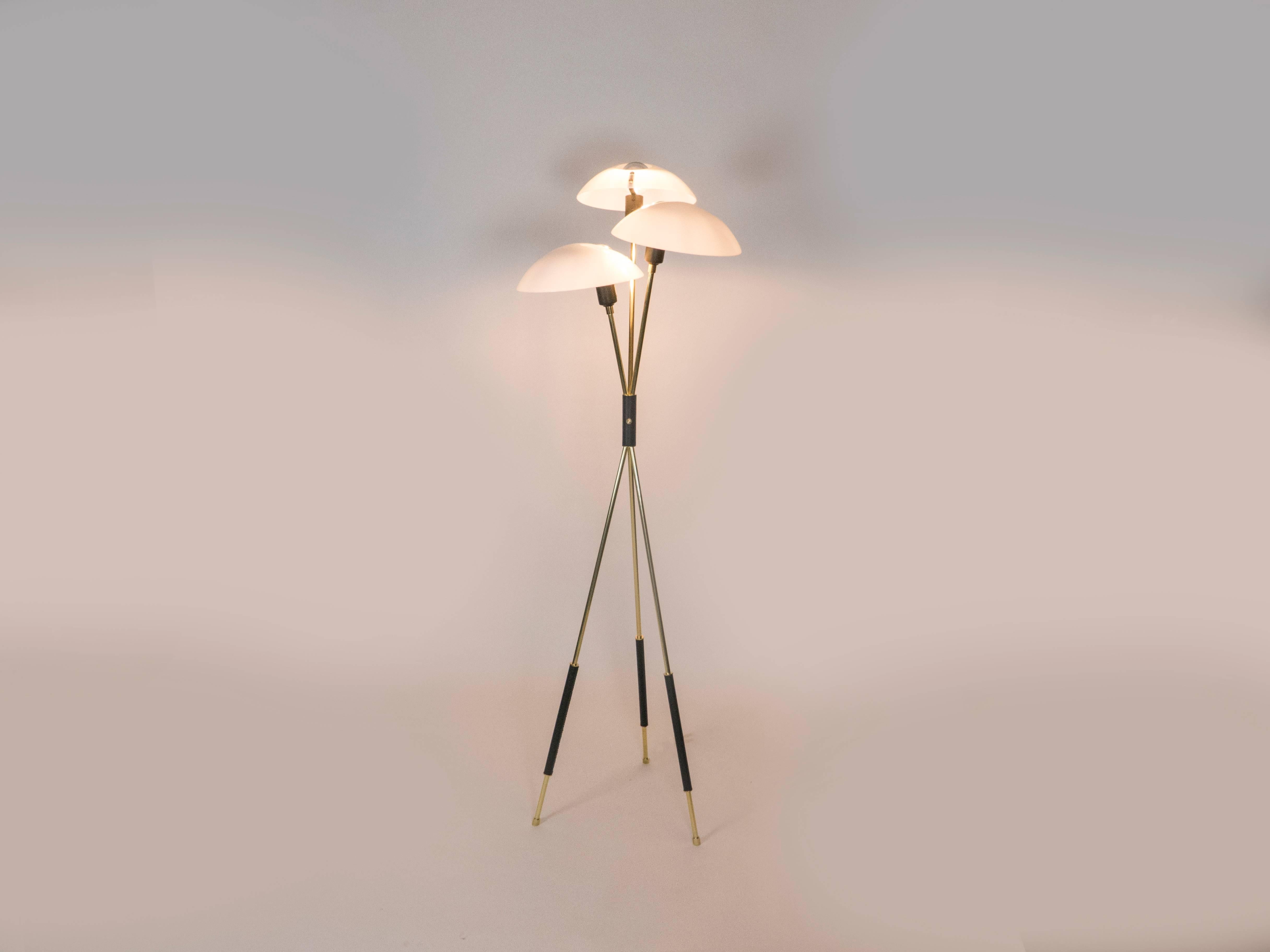 This elegant tripod floor lamp has a mid-century inspired design. The lamp has a brass body with hand-stitched leather accents. The light is diffused by acrylic diffusers which provide for direct down light and a soft diffused light in the room. The