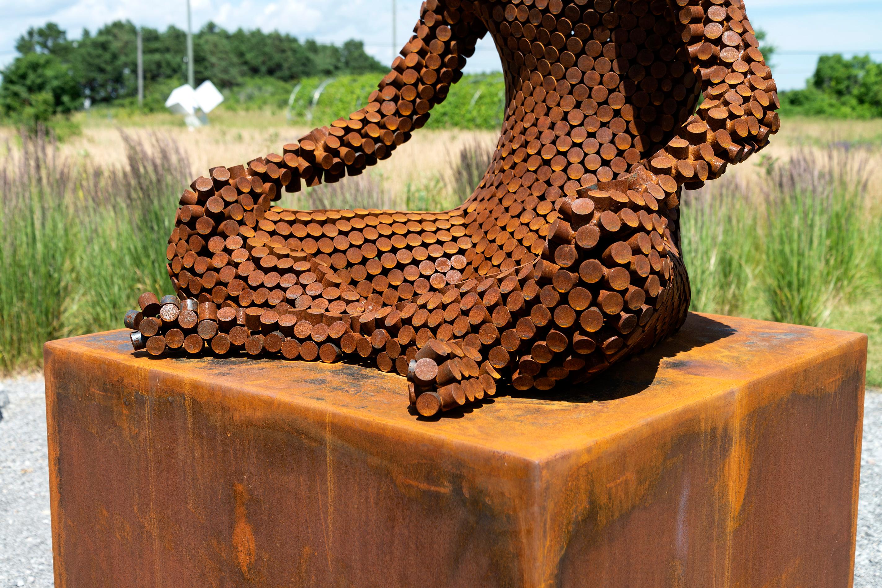 Una figura serena siede in una classica posizione yoga in questa nuova opera contemplativa dello scultore del Mississippi Jason Kimes. Forgiato da piccoli cerchi di acciaio corten, il pezzo ha assunto naturalmente una patina arrugginita dalle